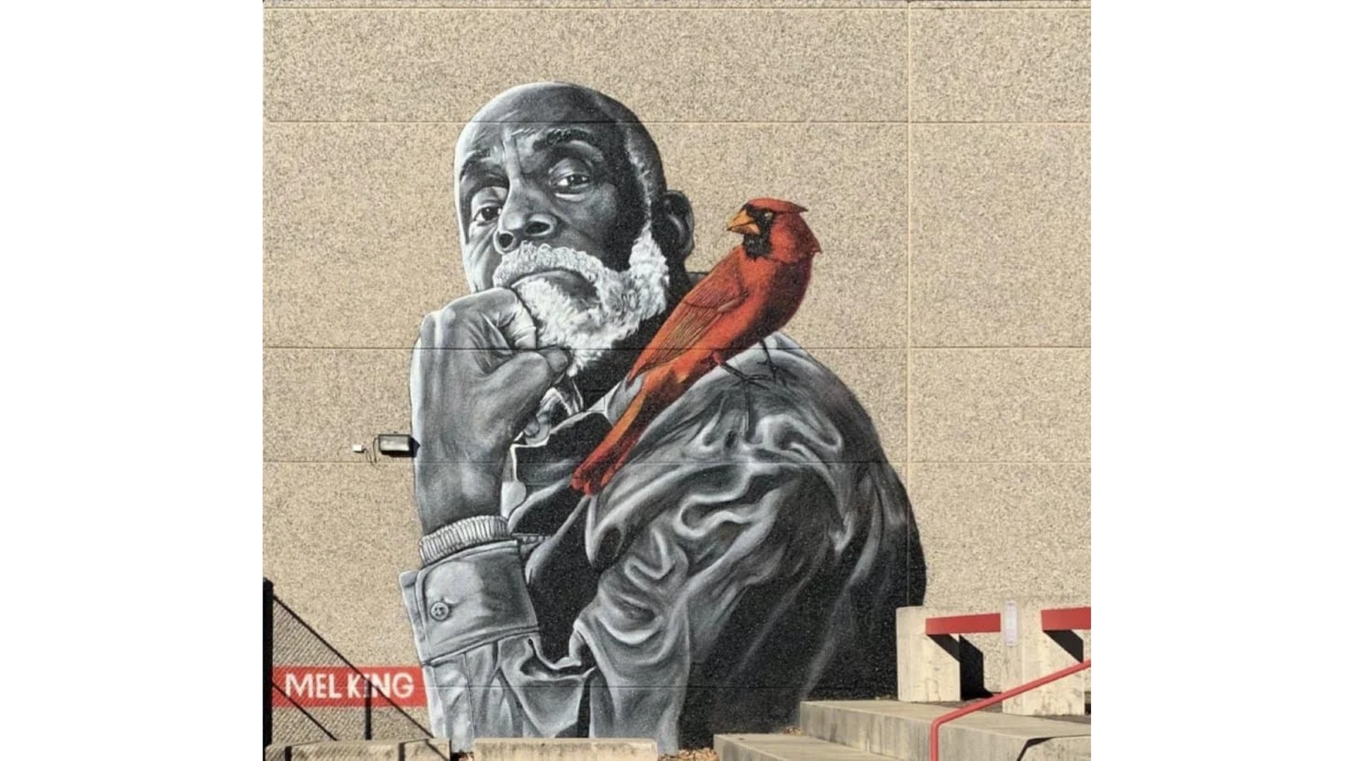 Street art mural of a man with a bird on his shoulder, holding a pipe, with a cityscape background.