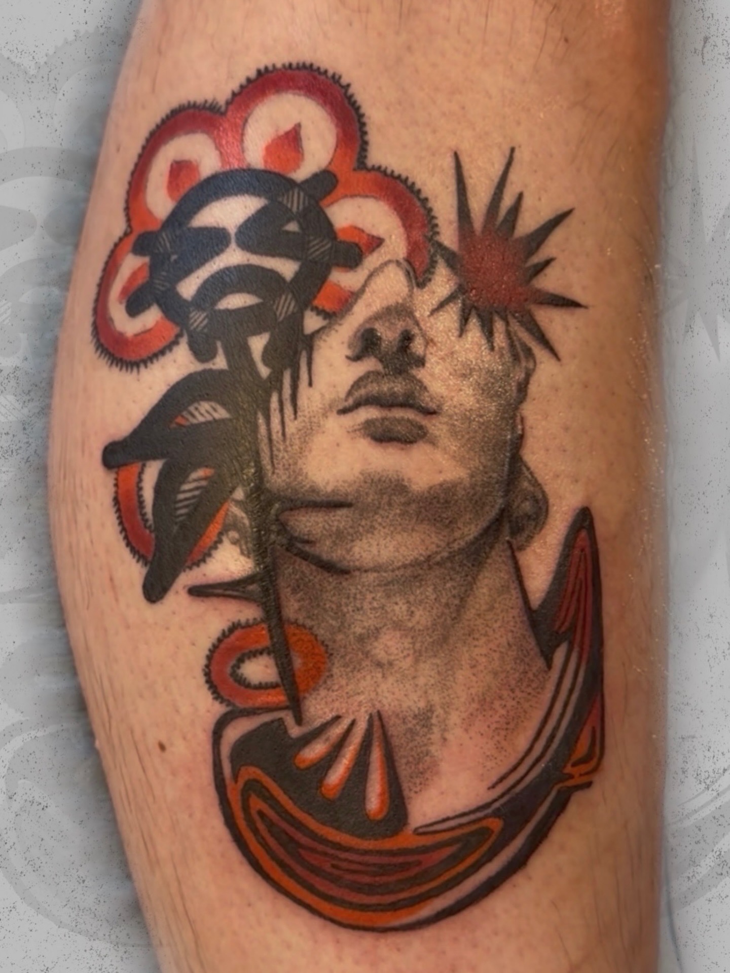 Tattoo of a woman's face with abstract colorful elements and black leaves around her head.