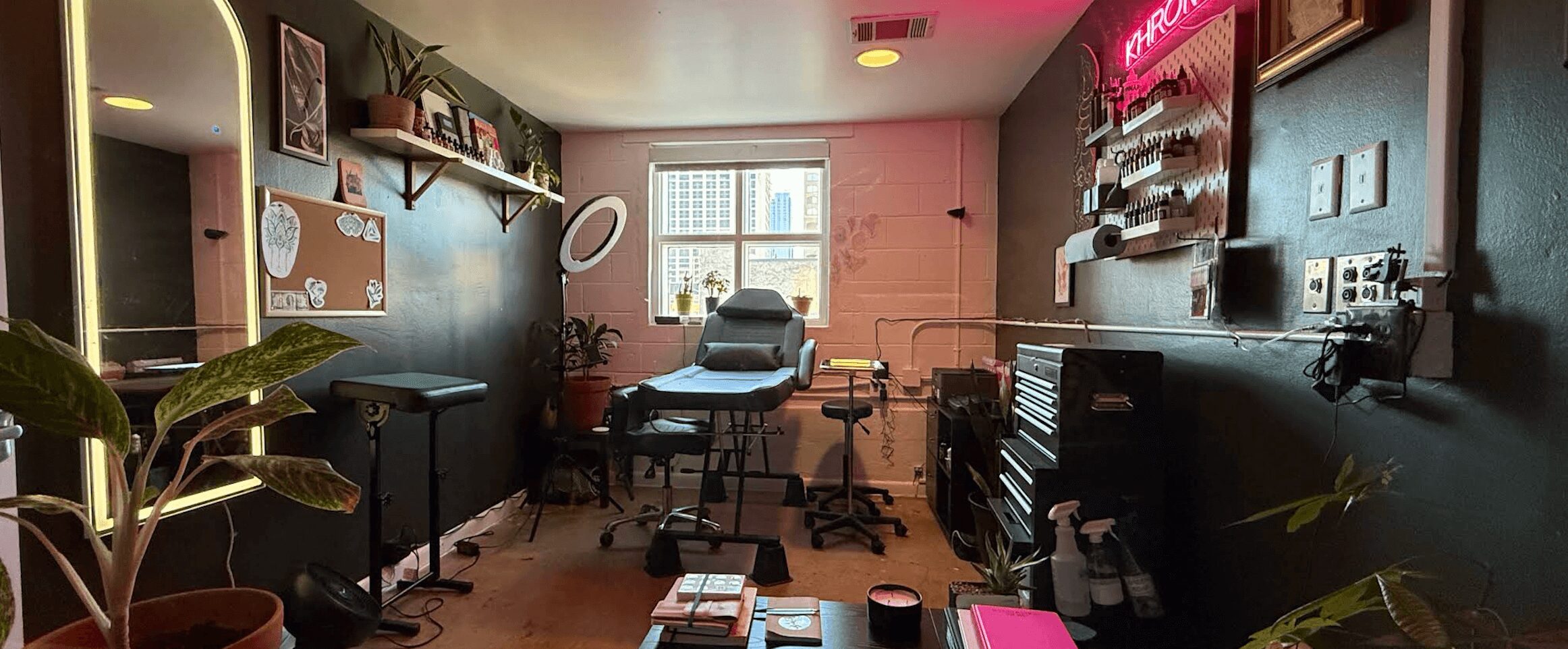 Office room with desk, chair, shelves, and window, decorated with plants and wall art.