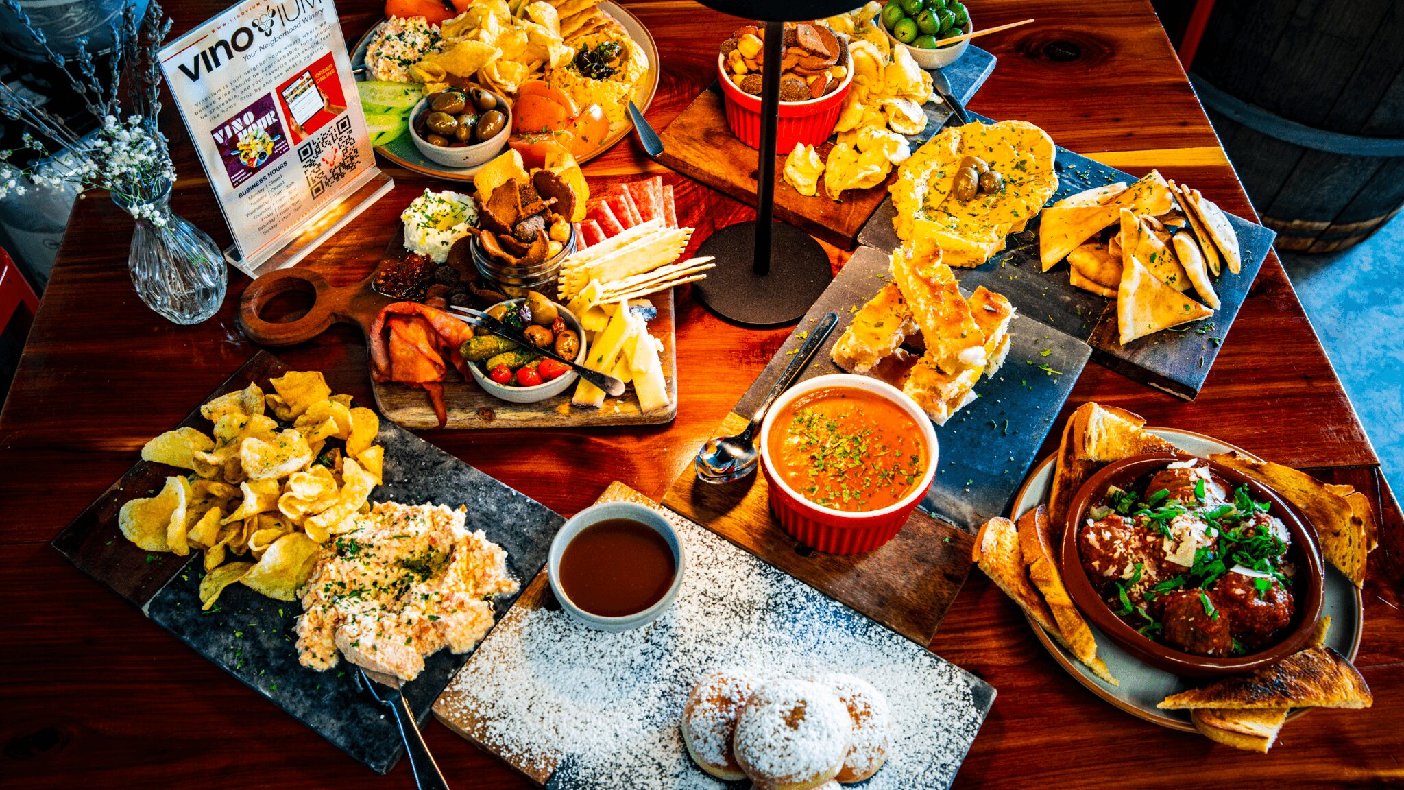 Assorted Japanese dishes including sushi, tempura, and sauces on a wooden table, with decorative elements and a menu card.