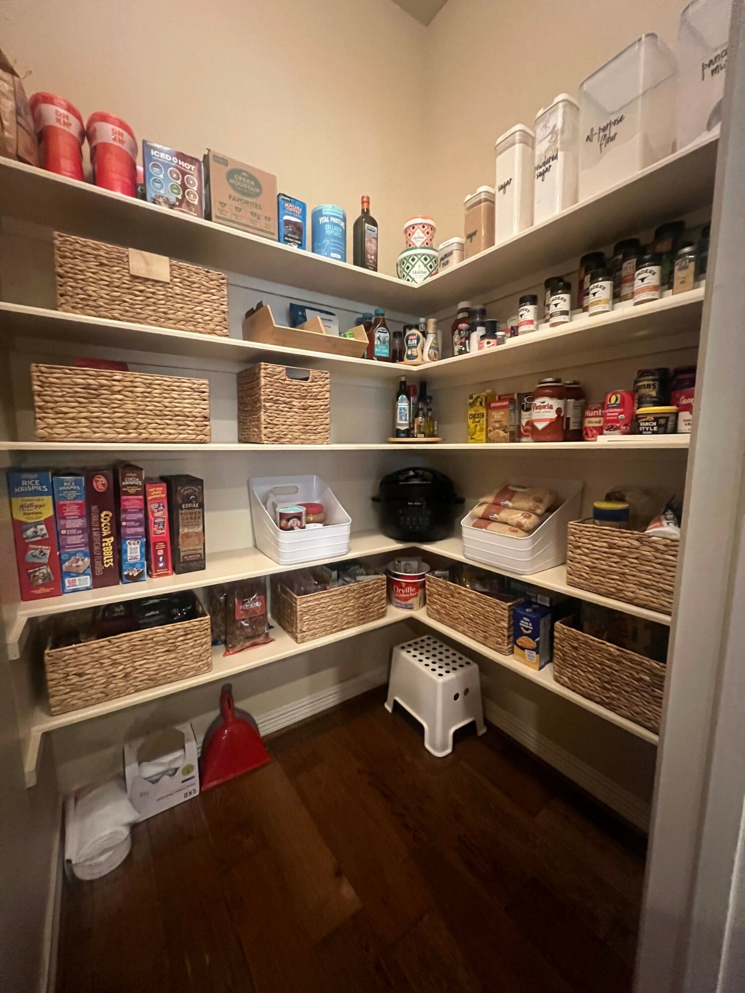 Shelves with various bottles, cans, and boxes, with a small white heater and a red object on the floor.
