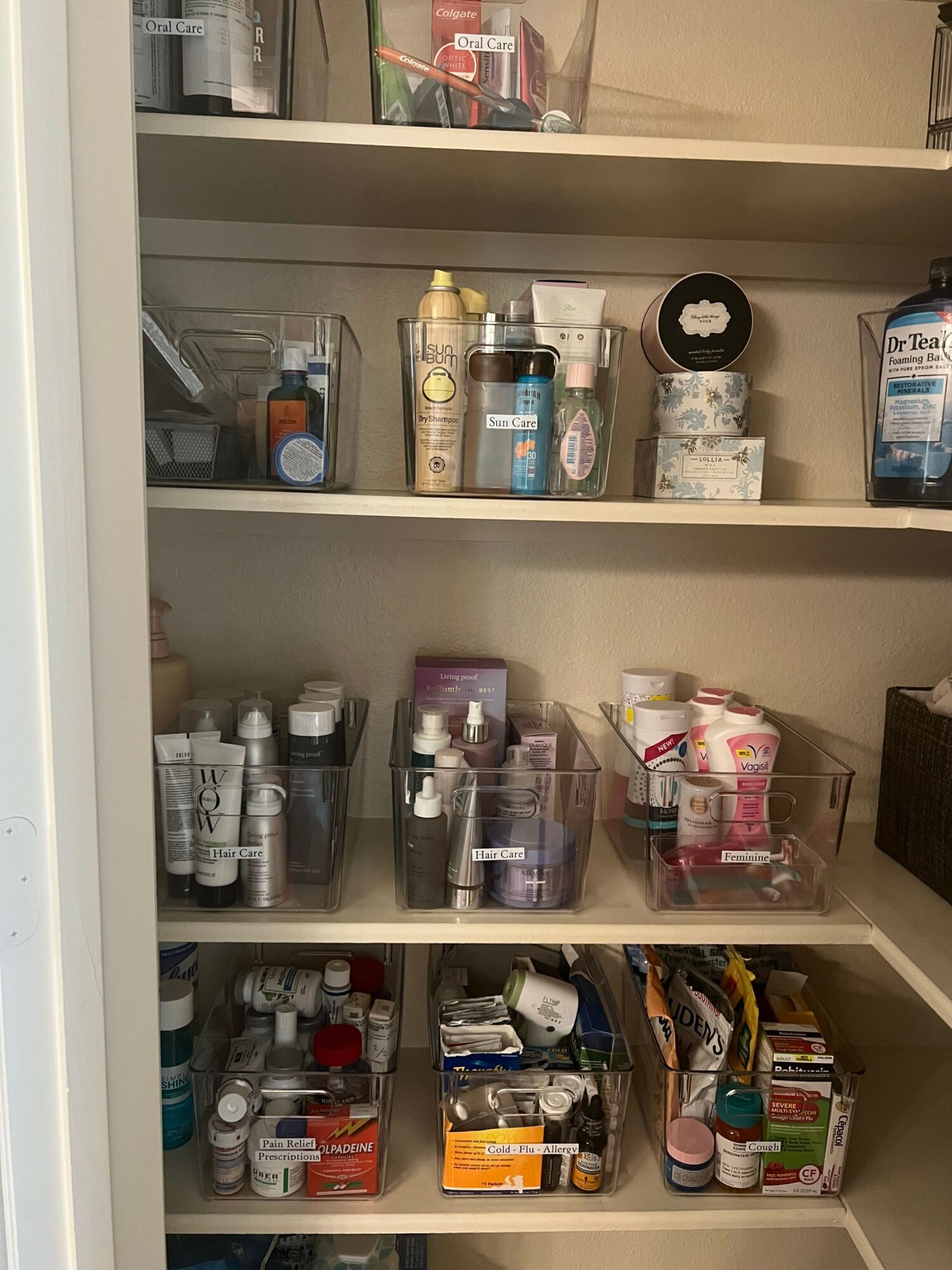 Shelves with various bottles, containers, and personal care items, organized in a bathroom or storage area.