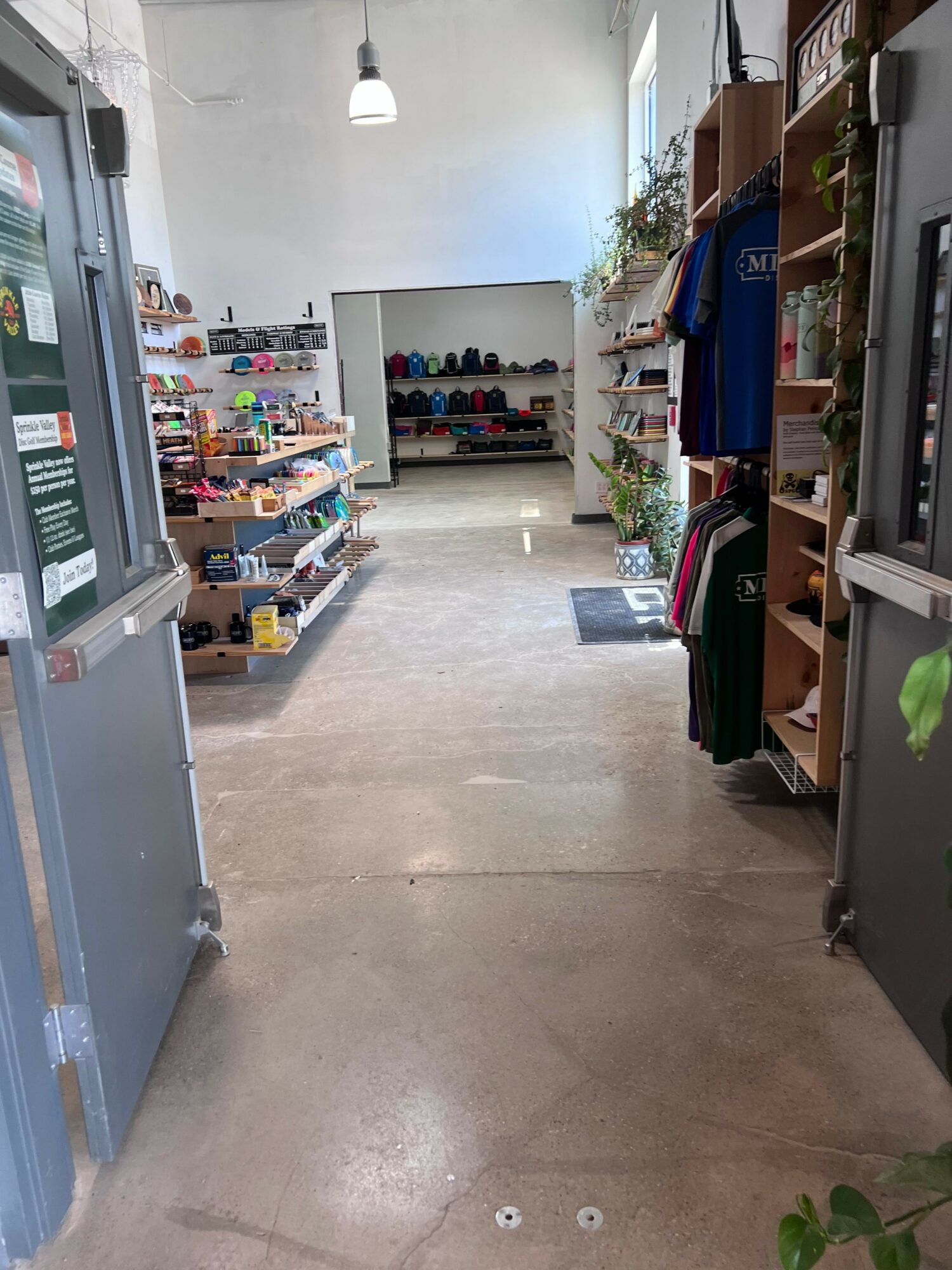 Indoor space with shelves, tables, and various items, including toys and books, in a well-lit room with a concrete floor.
