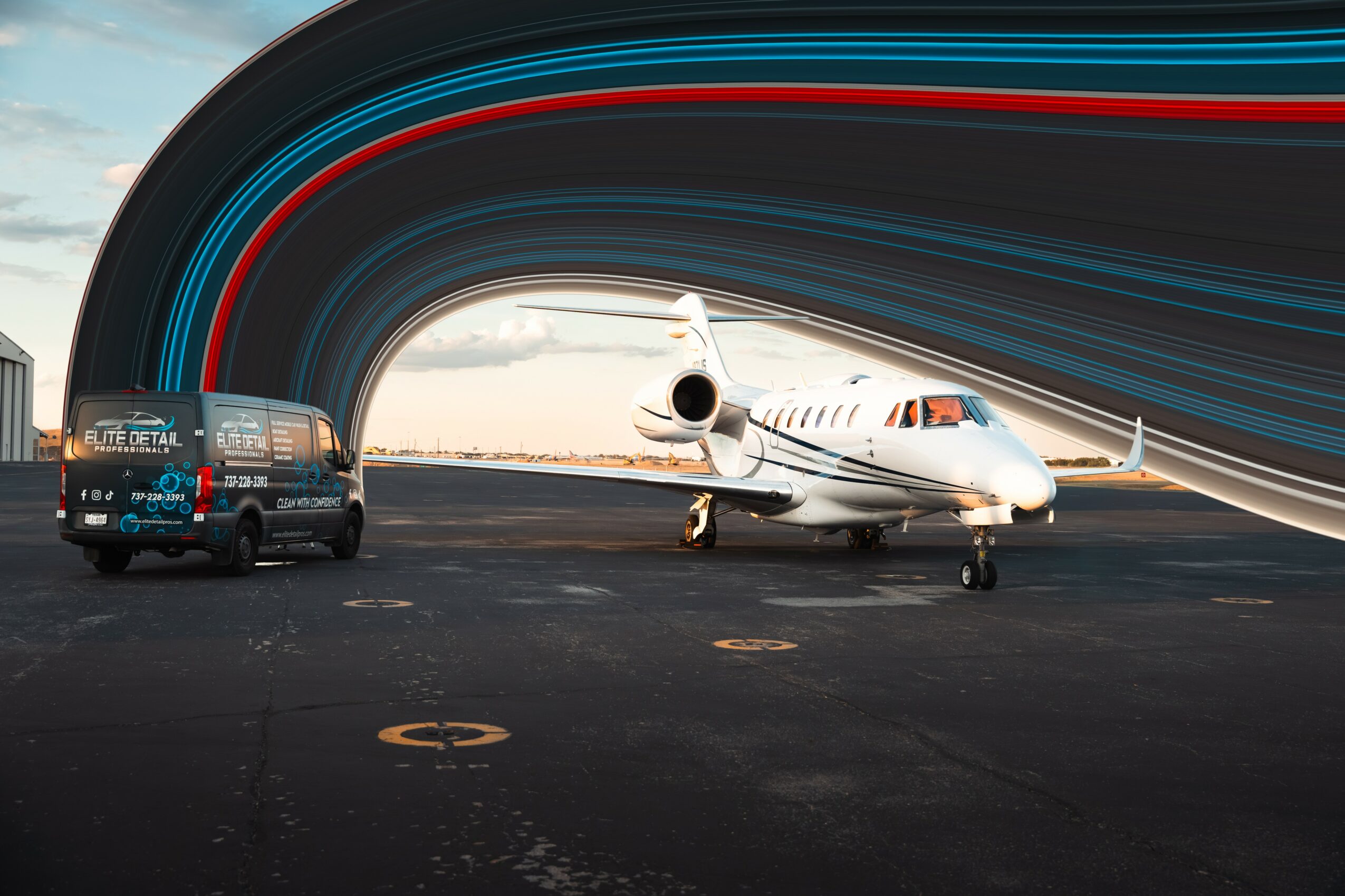 Private jet on tarmac with a vehicle nearby, colorful streaks in the sky background