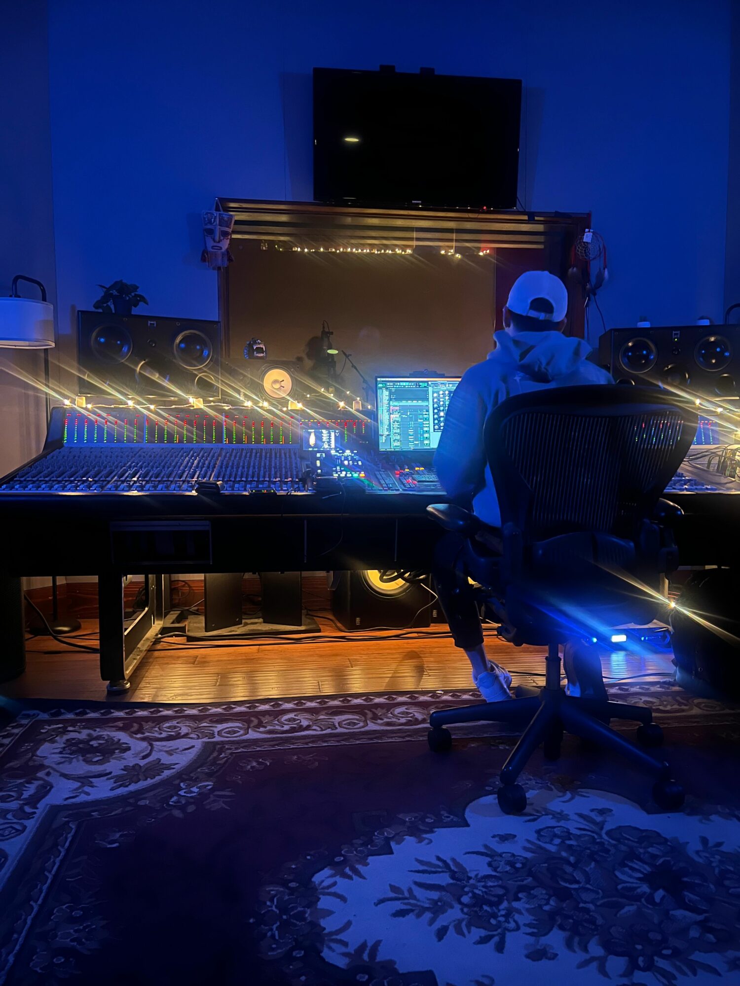 Stage with bright lights, a large screen, and a person sitting on a chair in a dimly lit venue.