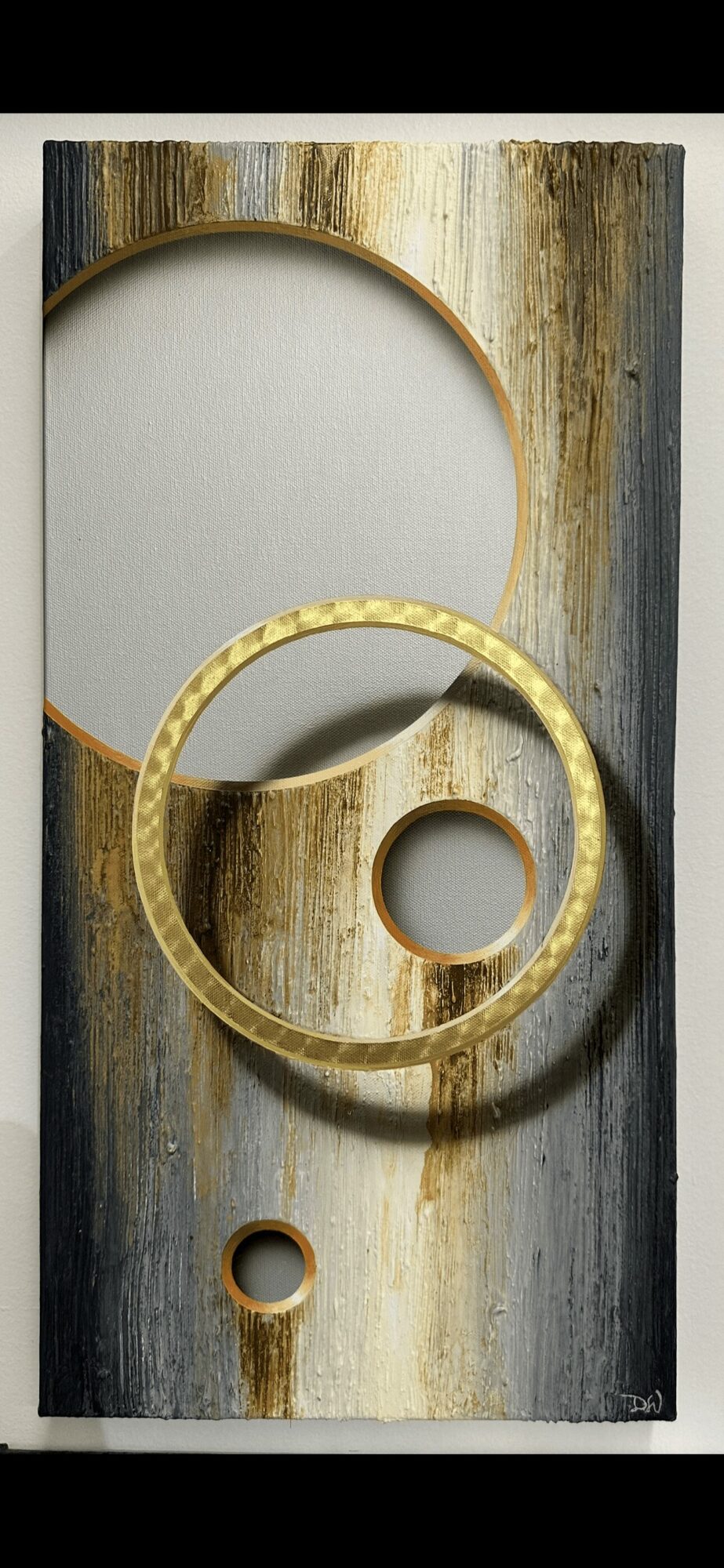 Vertical wooden panel with circular cutouts and a yellow ring, weathered surface with streaks of black, white, and brown.