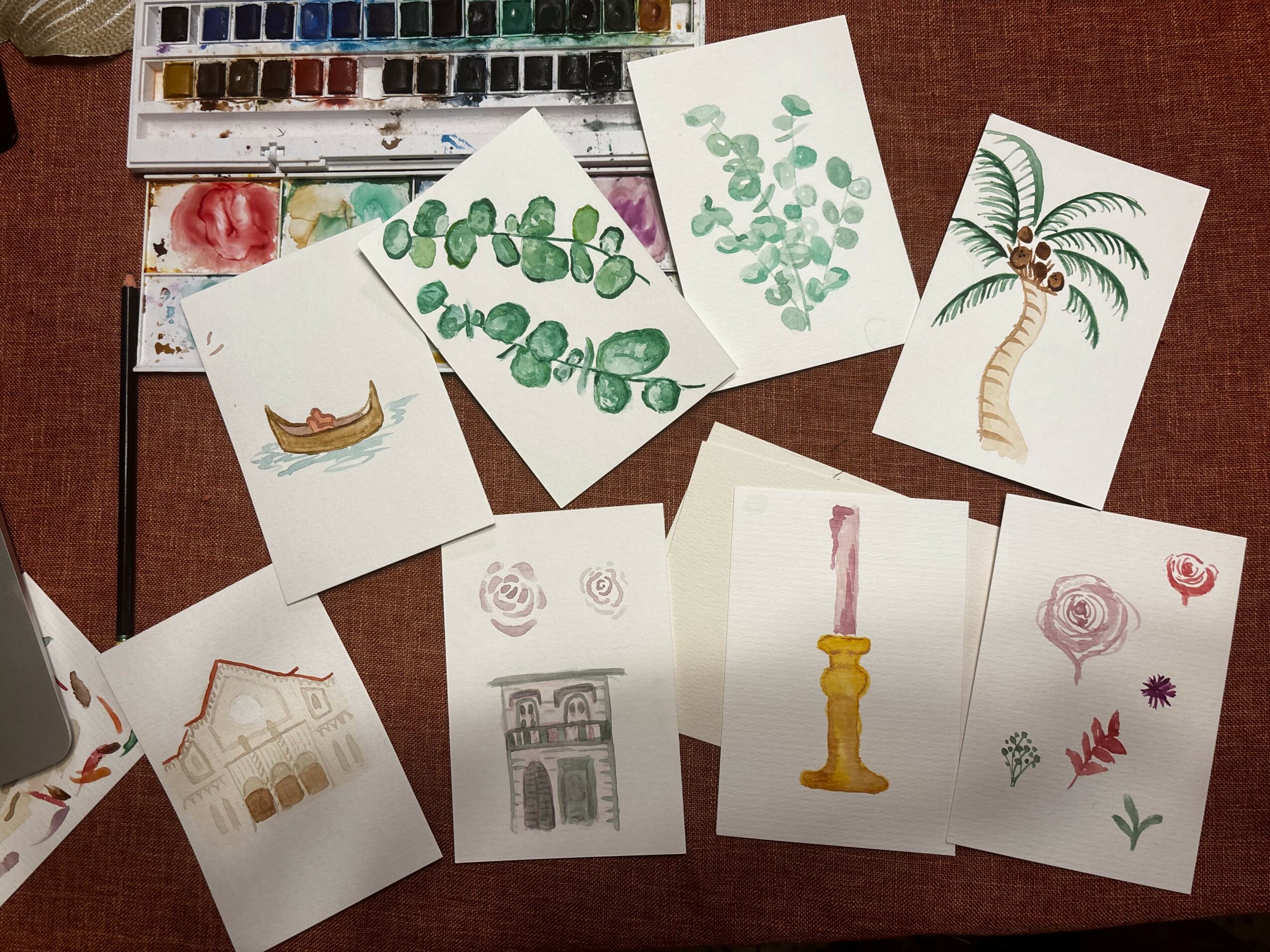Watercolor paintings of a boat, green leafy plants, a palm tree, a building, a candle, and flowers on white paper.