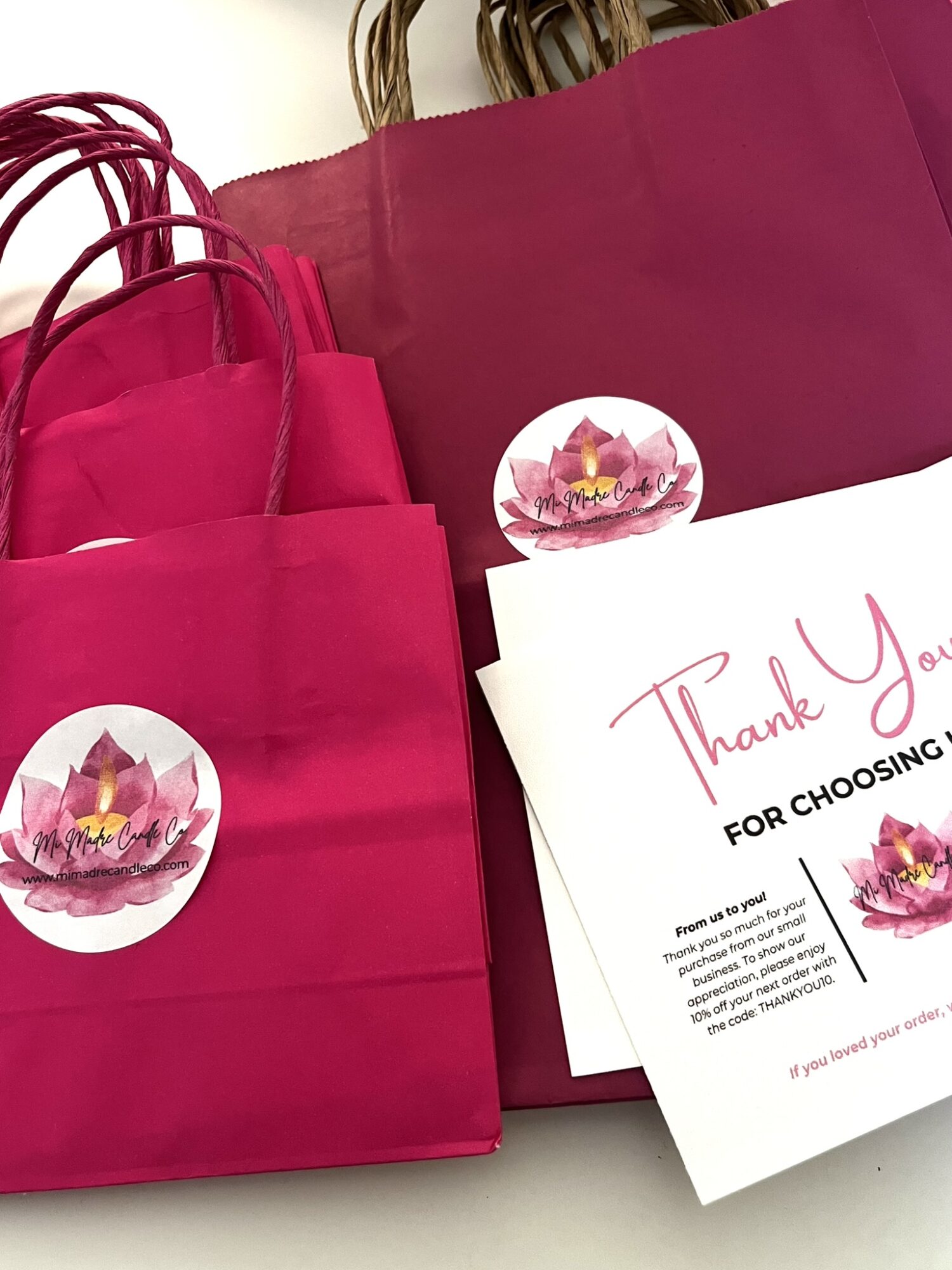 Pink gift bags and a thank you card with a lotus flower illustration.