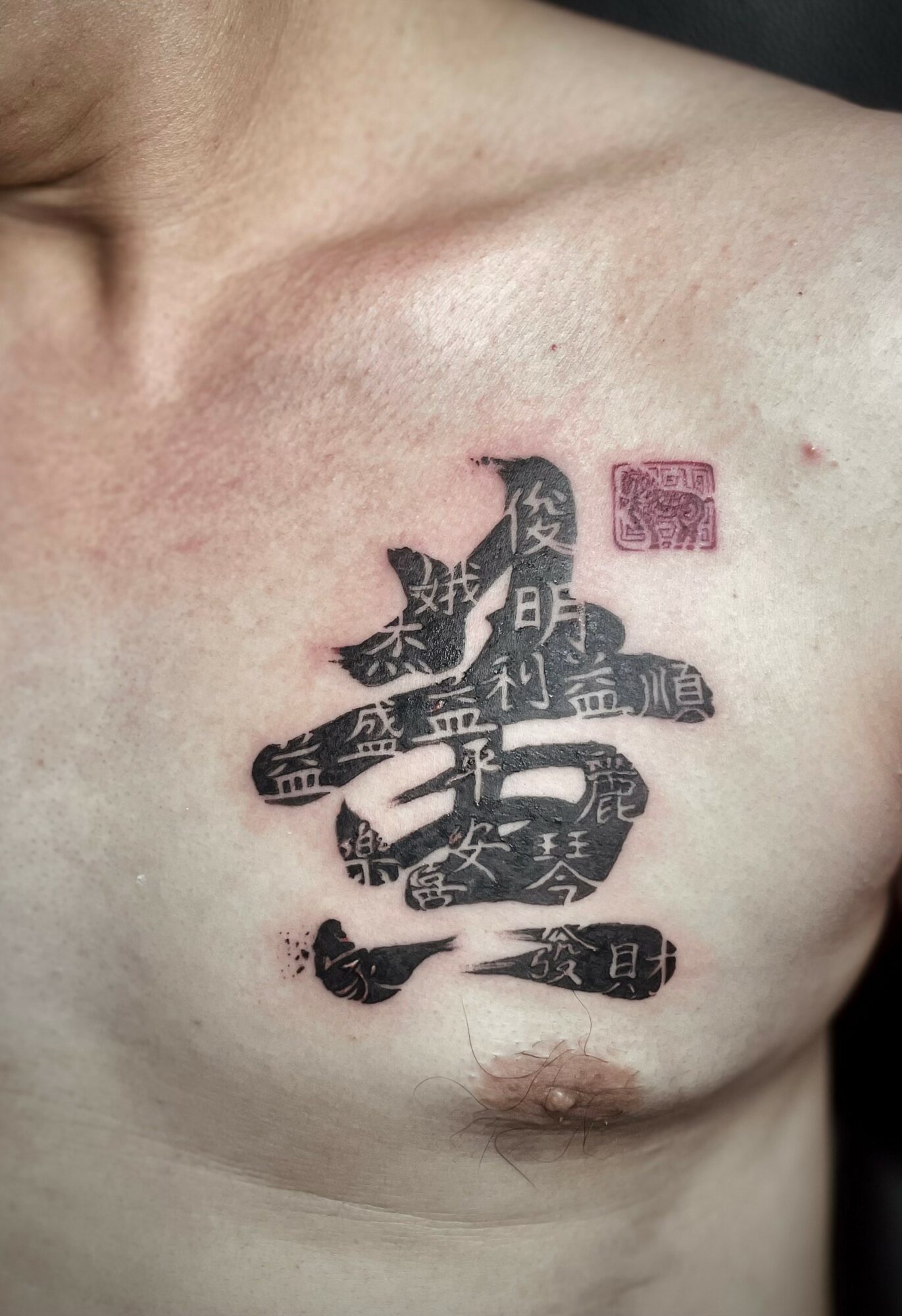 Tattoo of a snake with Japanese characters on a person's chest, near the shoulder and nipple.