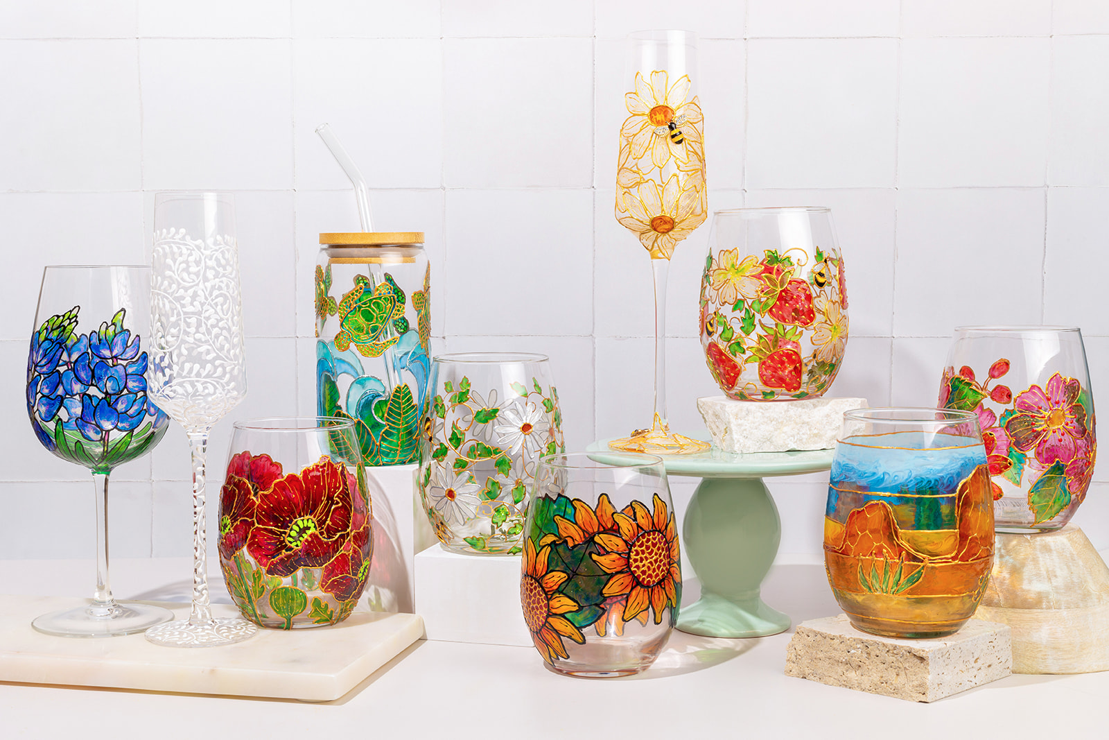 Various colorful glass vases and containers with floral and abstract designs on a white background.