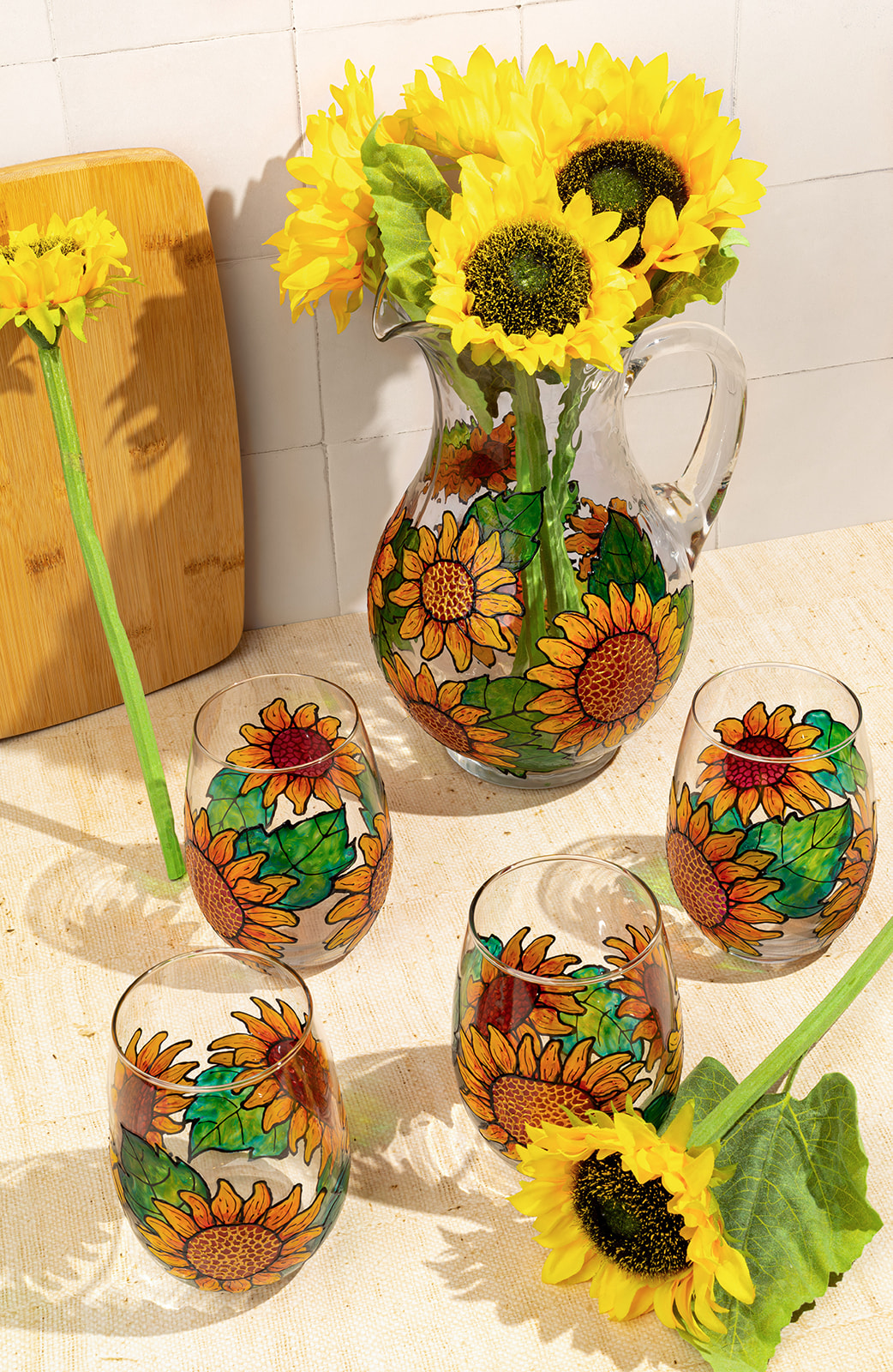 Sunflowers in a decorated vase and painted eggs with sunflower designs on a table.