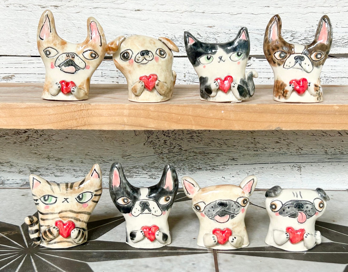 Two rows of ceramic dog figurines with glasses and red bows, displayed on wooden and tiled surfaces.