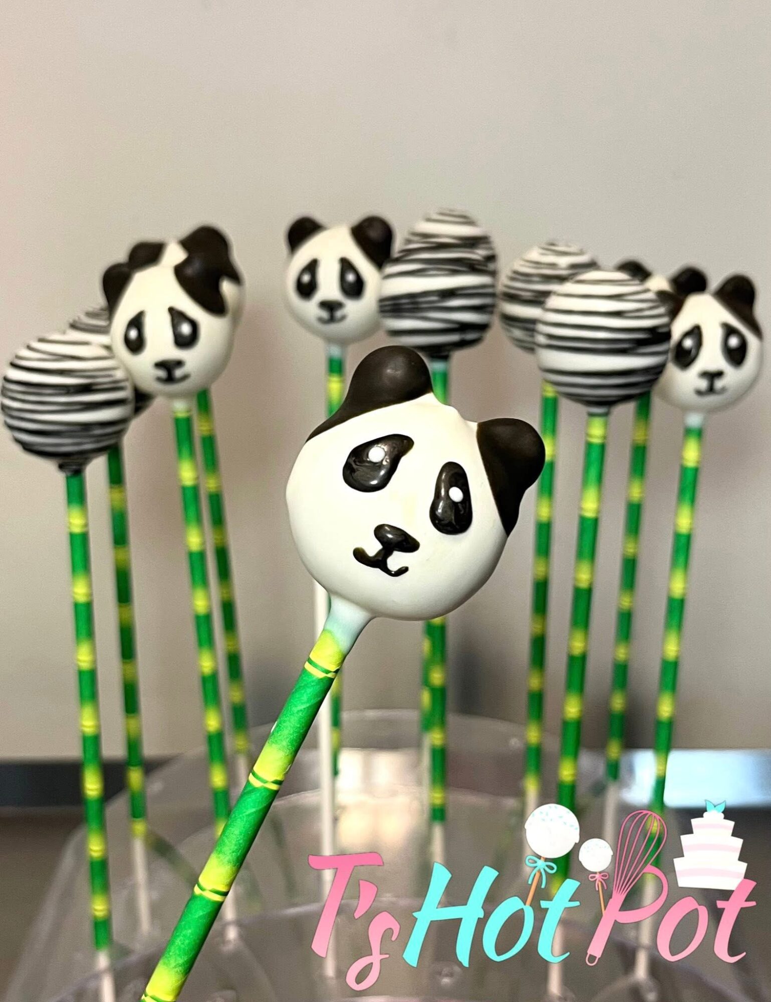 Panda-themed cake pops with striped and panda face designs on green and yellow sticks, arranged on a white surface.