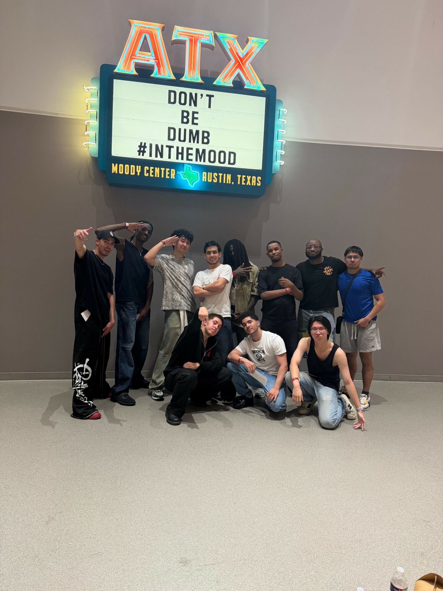 Group of people posing in front of a sign that reads 'ATL DUB DUB #INTHEDOOM MOOD' at a venue or event.