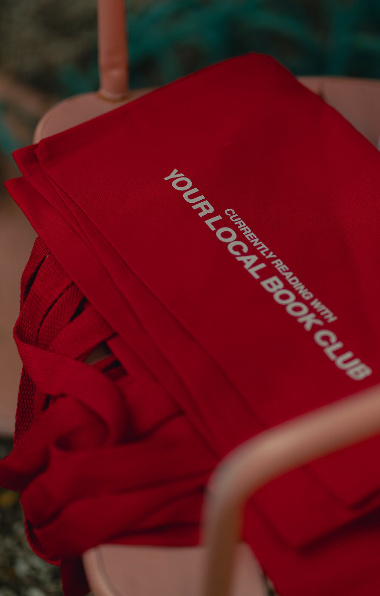 Red fabric with white text reading 'YOUR LOCAL BOOK CLUB' and additional smaller text, on a surface.