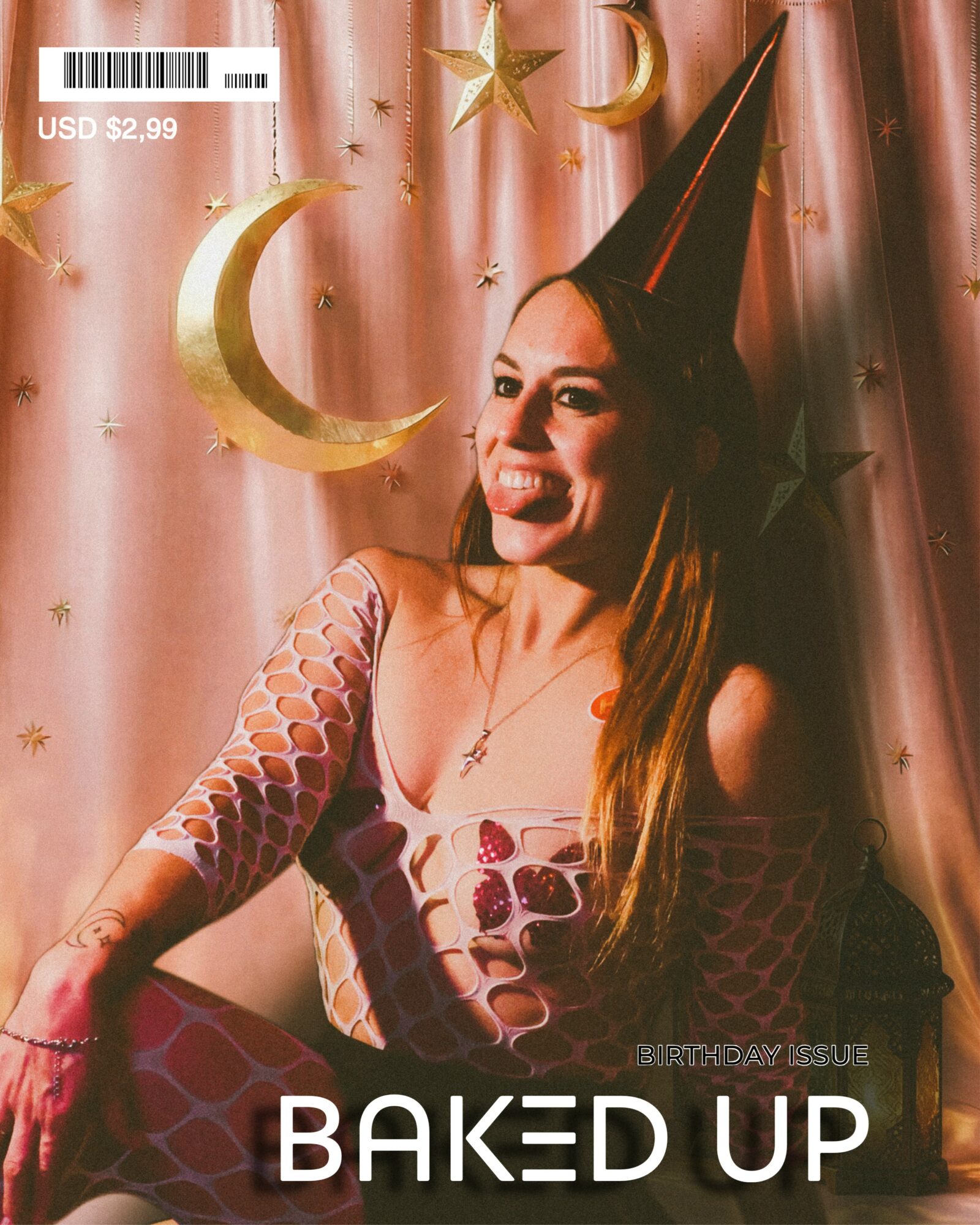 Woman in party hat smiling, sitting in front of pink curtain with moon and star decorations.