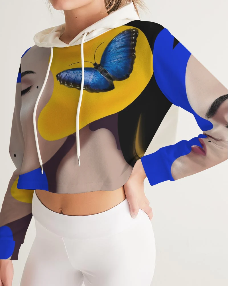 Person wearing a colorful hoodie with a blue butterfly design, white pants, and a beige background.