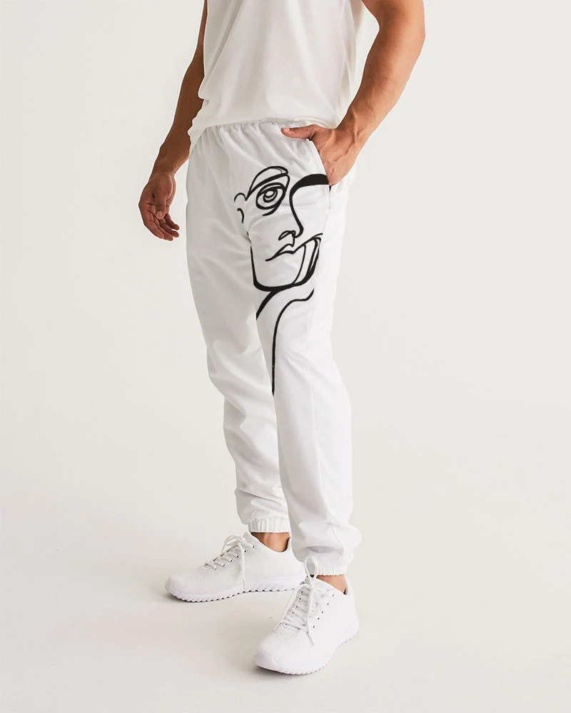 Person wearing white pants with a black line drawing of a face on the side, standing with one hand in pocket, white sneakers, plain background.