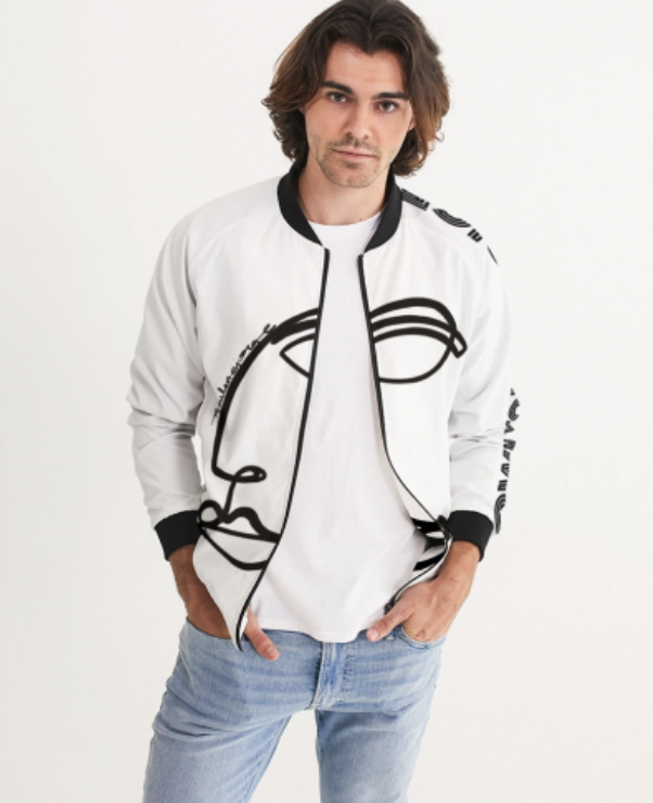 Young man with shoulder-length hair wearing a white jacket with black accents and a graphic design, standing against a plain background.