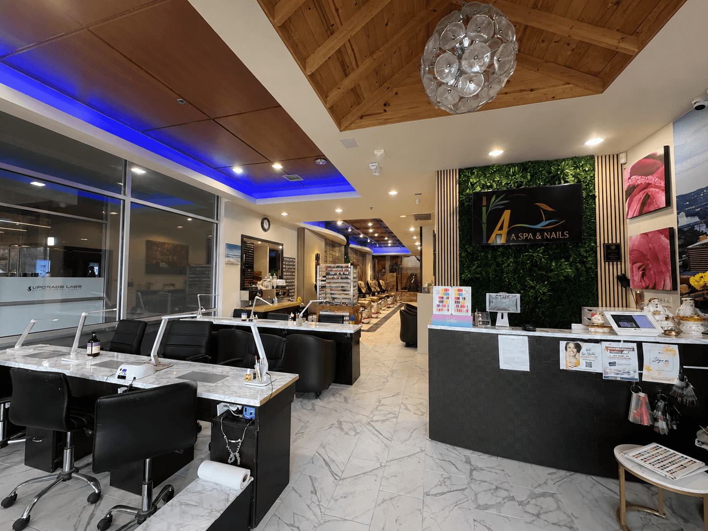 Salon reception area with black chairs, marble floor, green wall, and display shelves, illuminated by ceiling lights and blue LED accents.