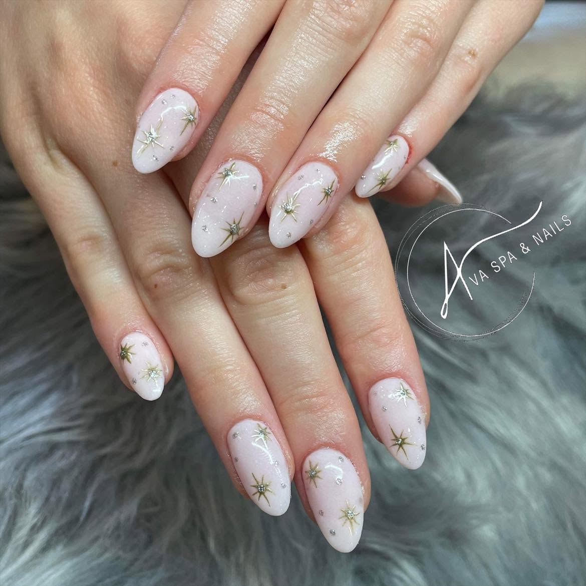 Hands with white nails decorated with gold starburst designs, resting on a furry surface.