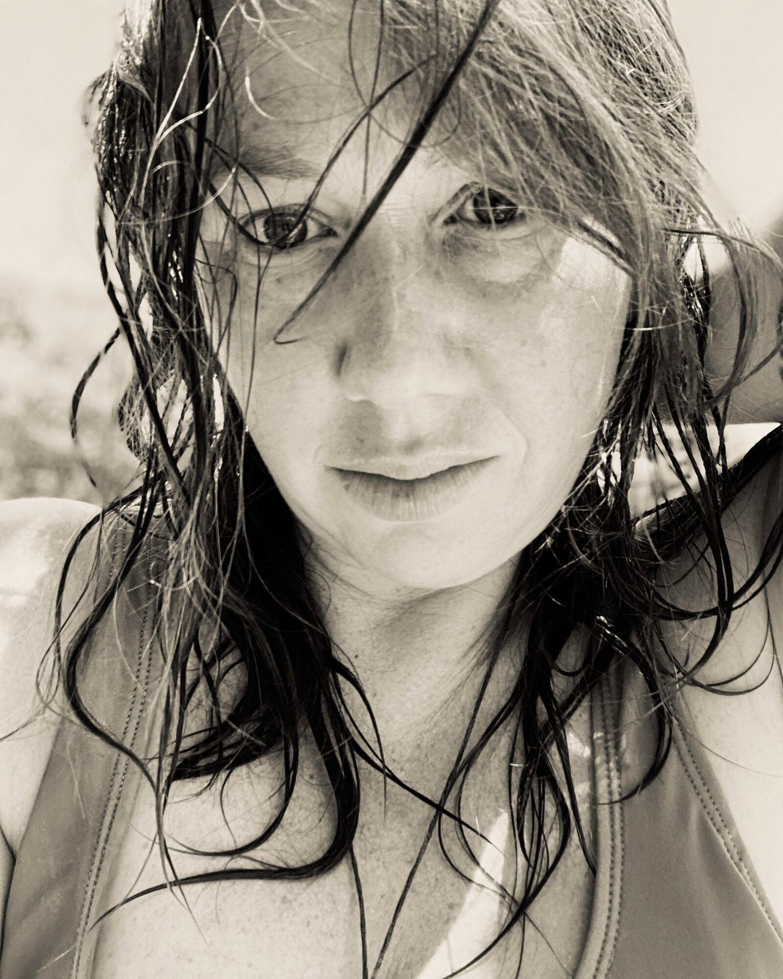 Close-up of a woman with wet hair, looking at the camera, in black and white.