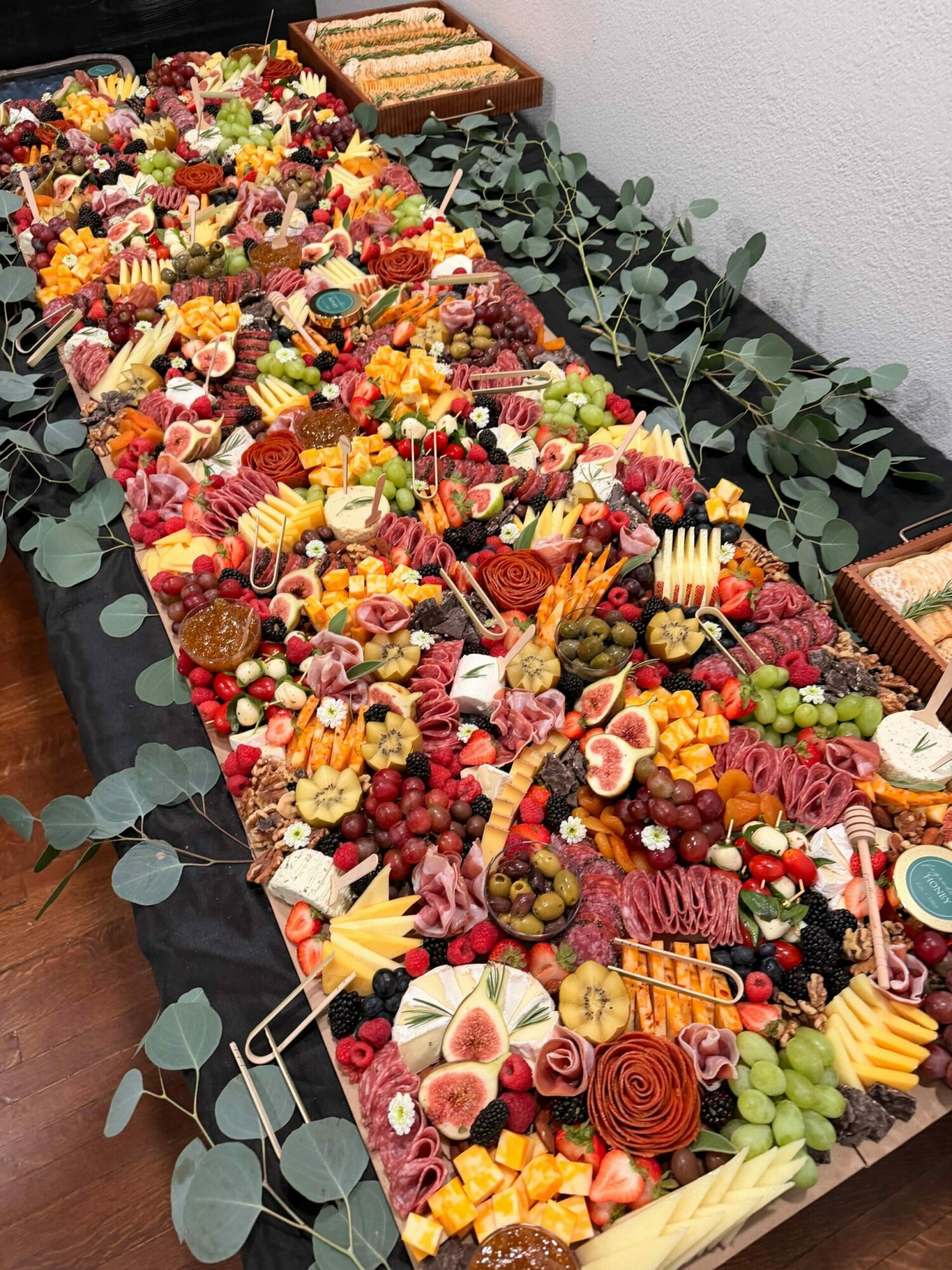 Colorful fruit and flower arrangement on a table with greenery, viewed from above.
