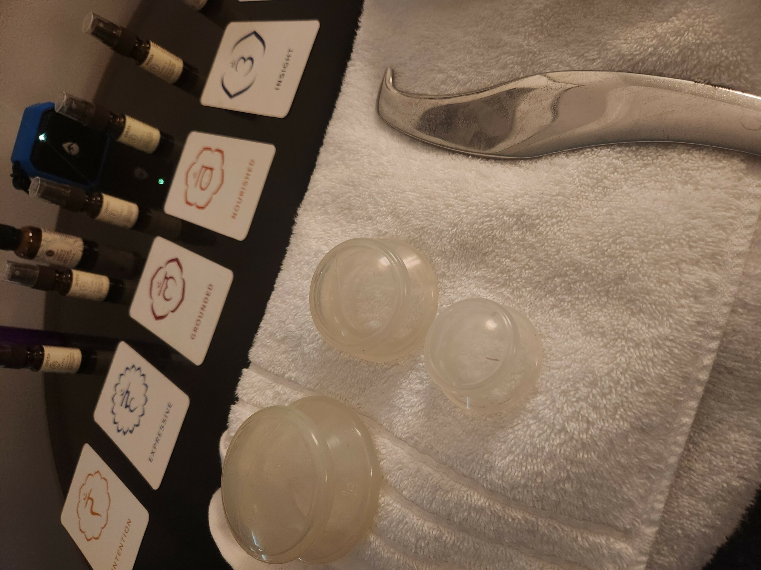 Medical or skincare tools and containers on a towel, with a metal instrument at the top right.
