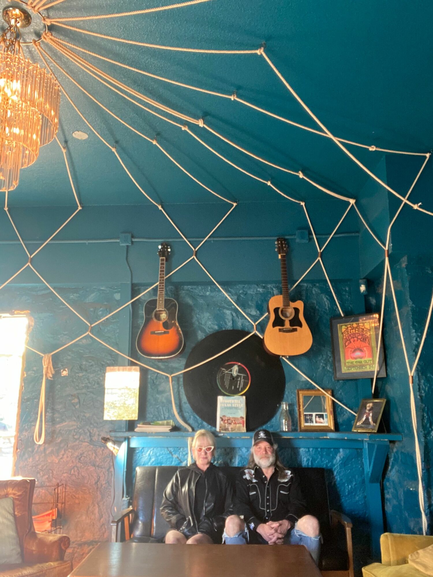 People sitting in a room with musical instruments and artwork on the walls, illuminated by warm lighting.