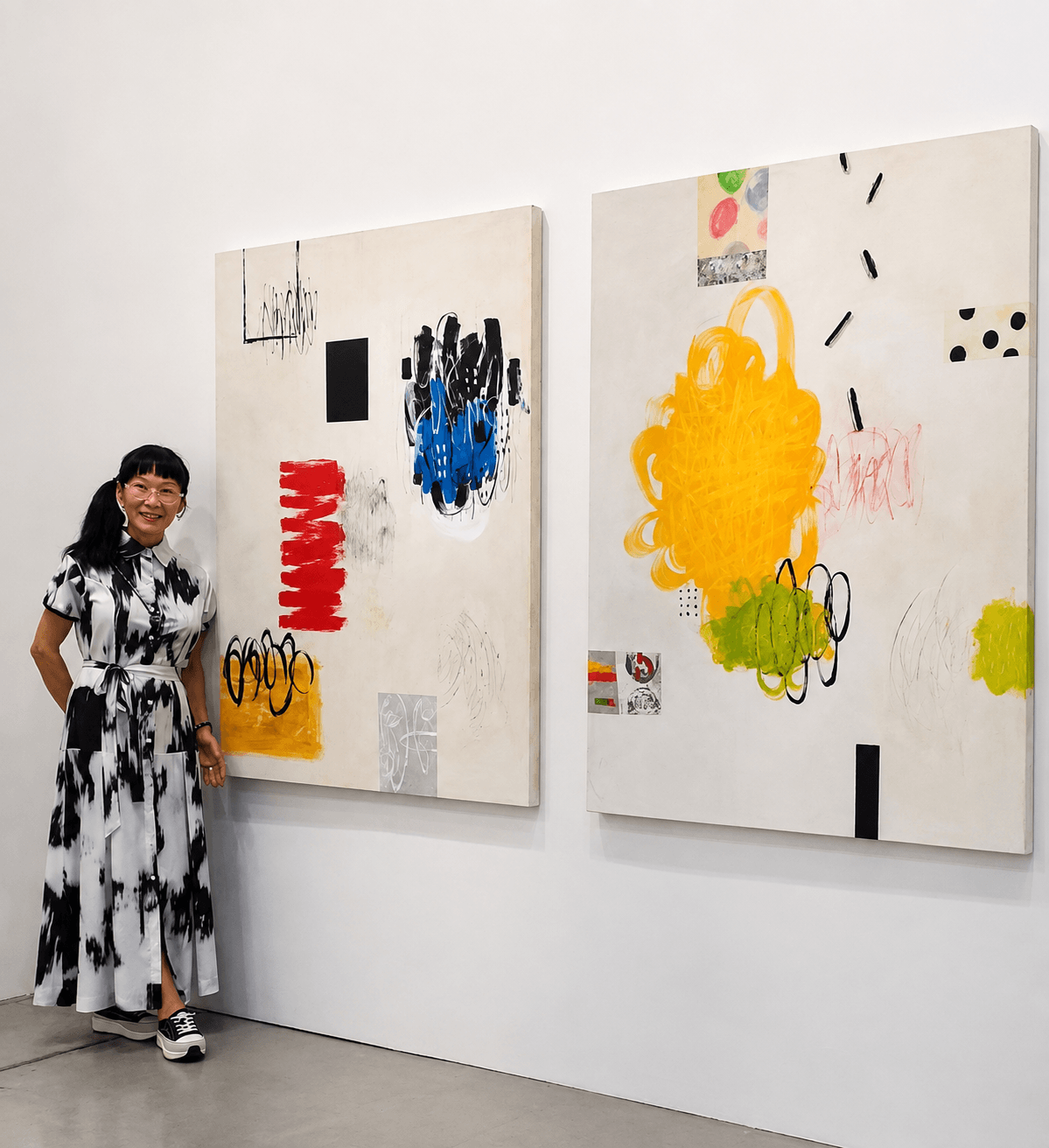 Girl in black and white dress standing next to two abstract paintings on a white wall.