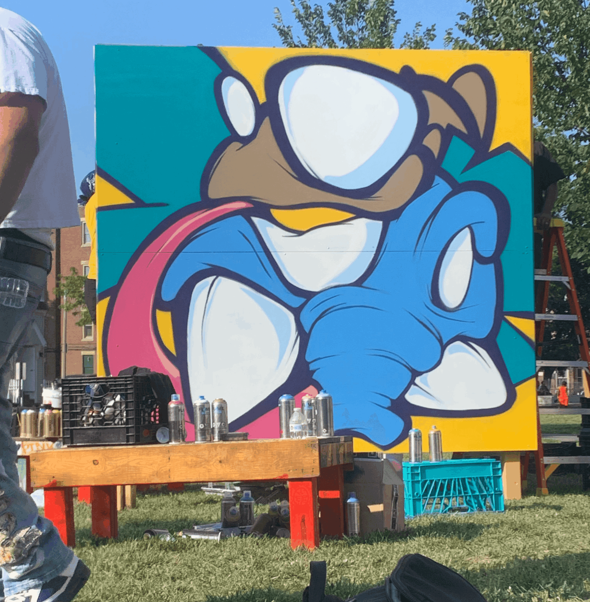 Colorful graffiti art of a cartoon character with glasses, a pink tongue, and a blue hand, on a yellow background.