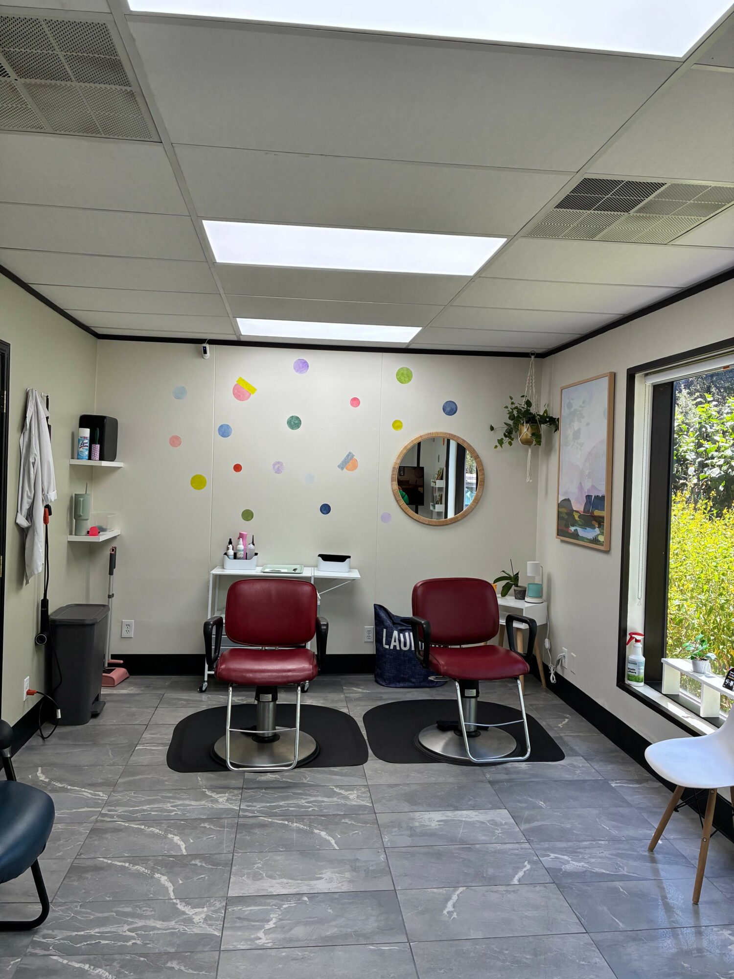 Office room with two red chairs, a window, and colorful wall decorations, viewed from the side.