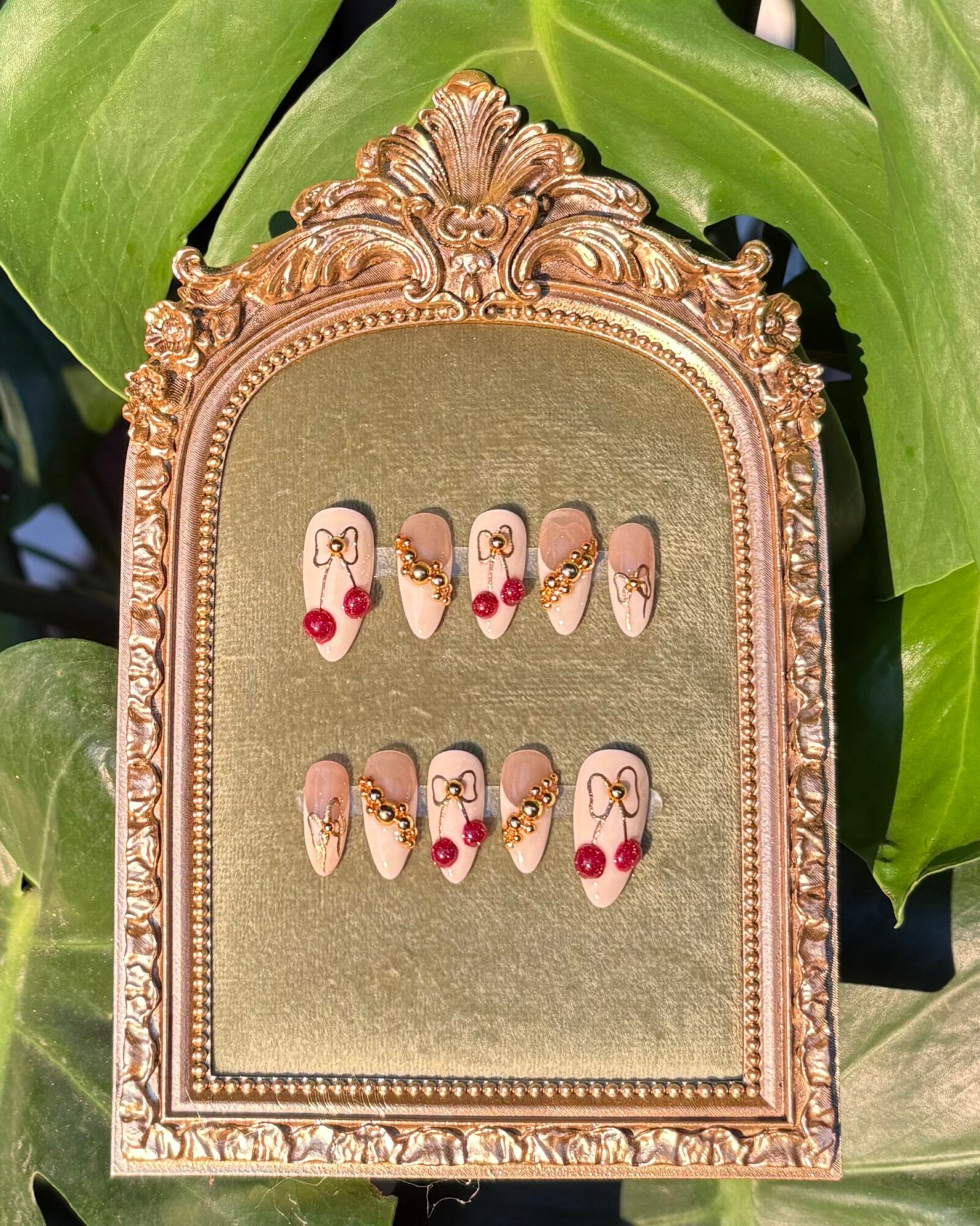 Decorative frame with ten nail art designs on a green background, featuring floral and heart motifs, with red accents.