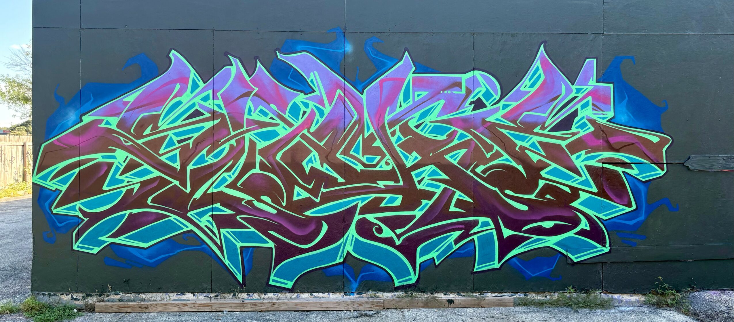 Colorful graffiti with abstract shapes and sharp lines on a dark wall.
