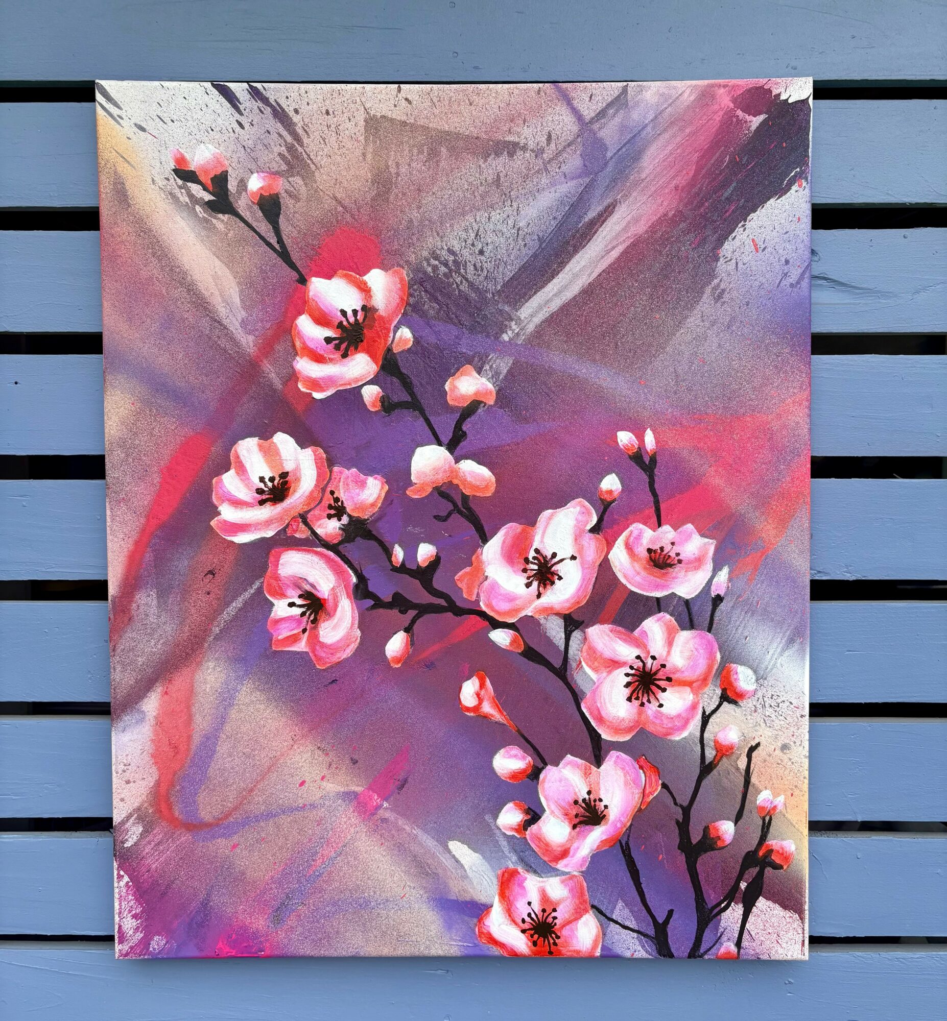 Pink cherry blossoms on dark branches against a colorful abstract background with pink, purple, and gray hues.