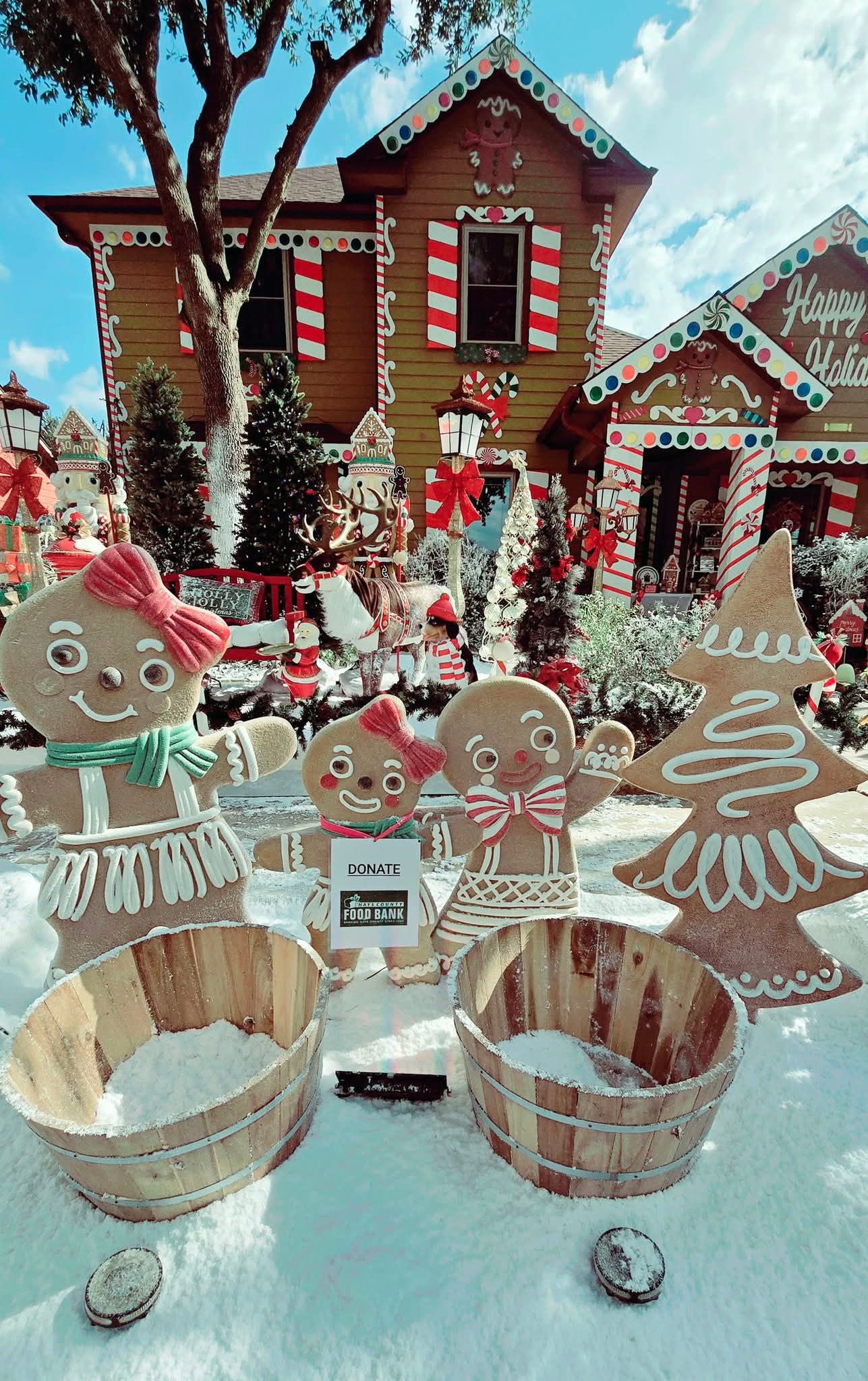 Gingerbread house decorated for Christmas with gingerbread figures, trees, and presents, under a blue sky with clouds.