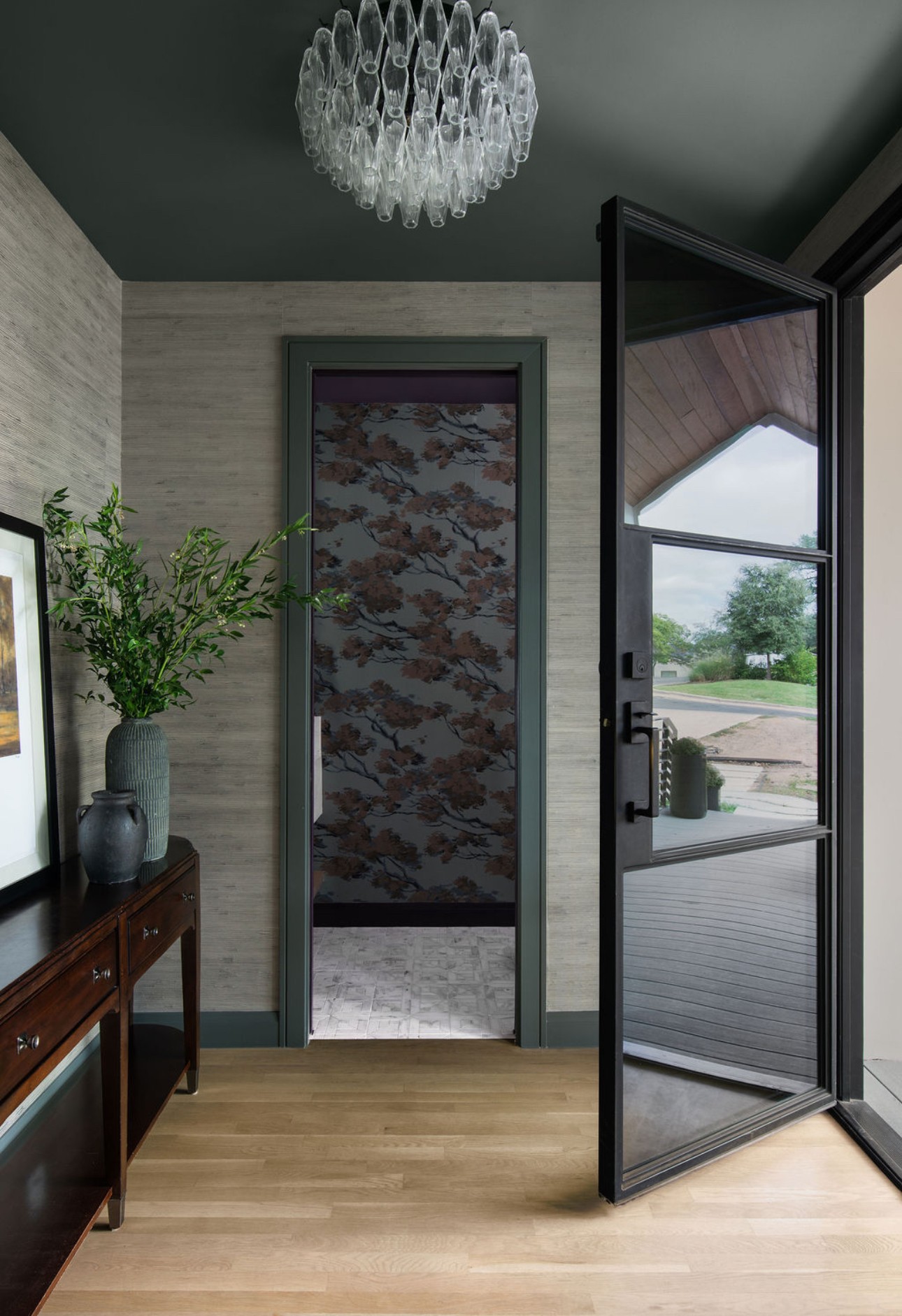 Interior view with a door leading outside, a glass door open, a wooden floor, and a chandelier on the ceiling.