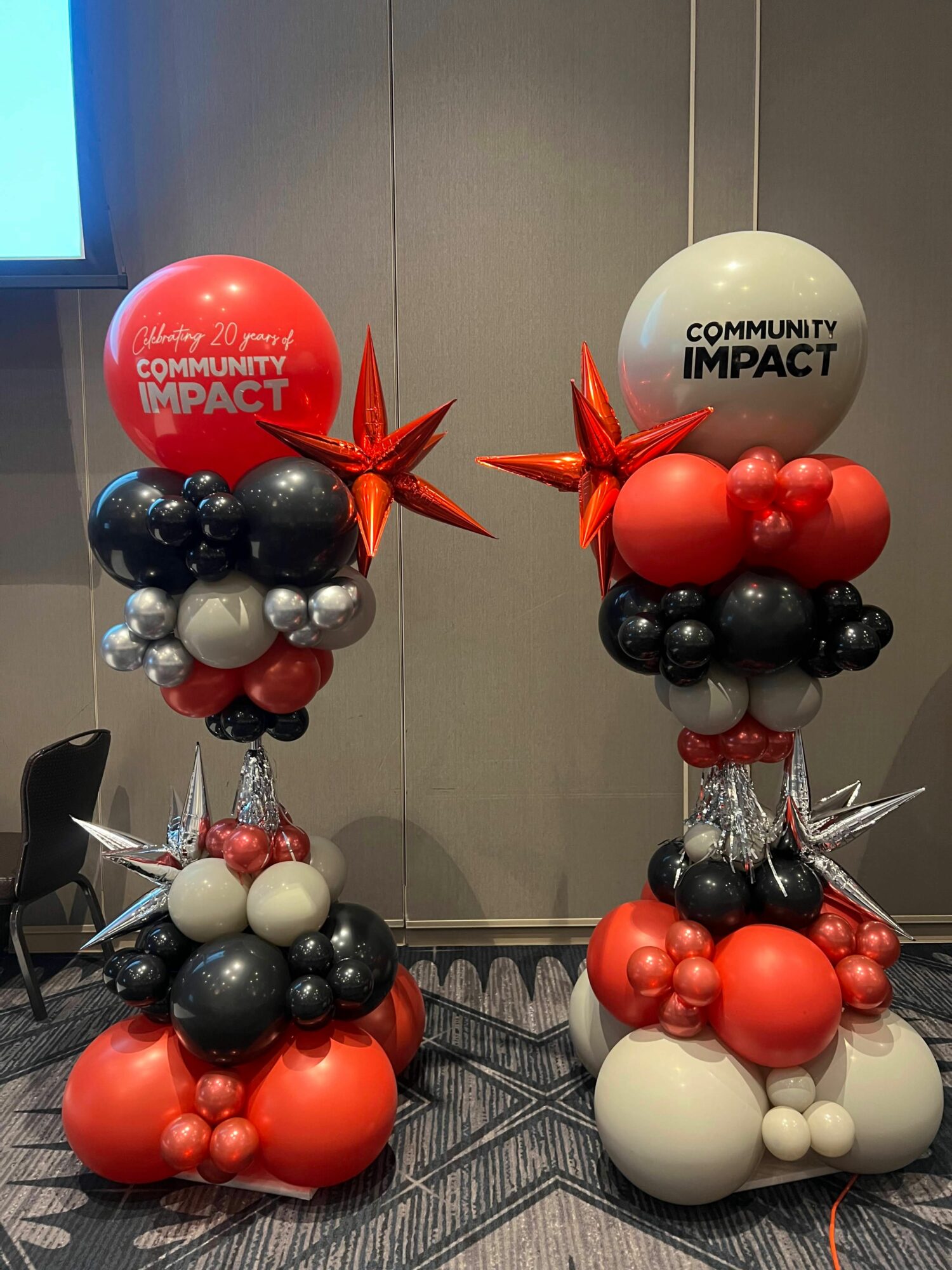 Decorative balloon arrangement with red, black, white, and orange balloons, and a white balloon with 'COMBAT IMPACT' text, on a patterned carpet.
