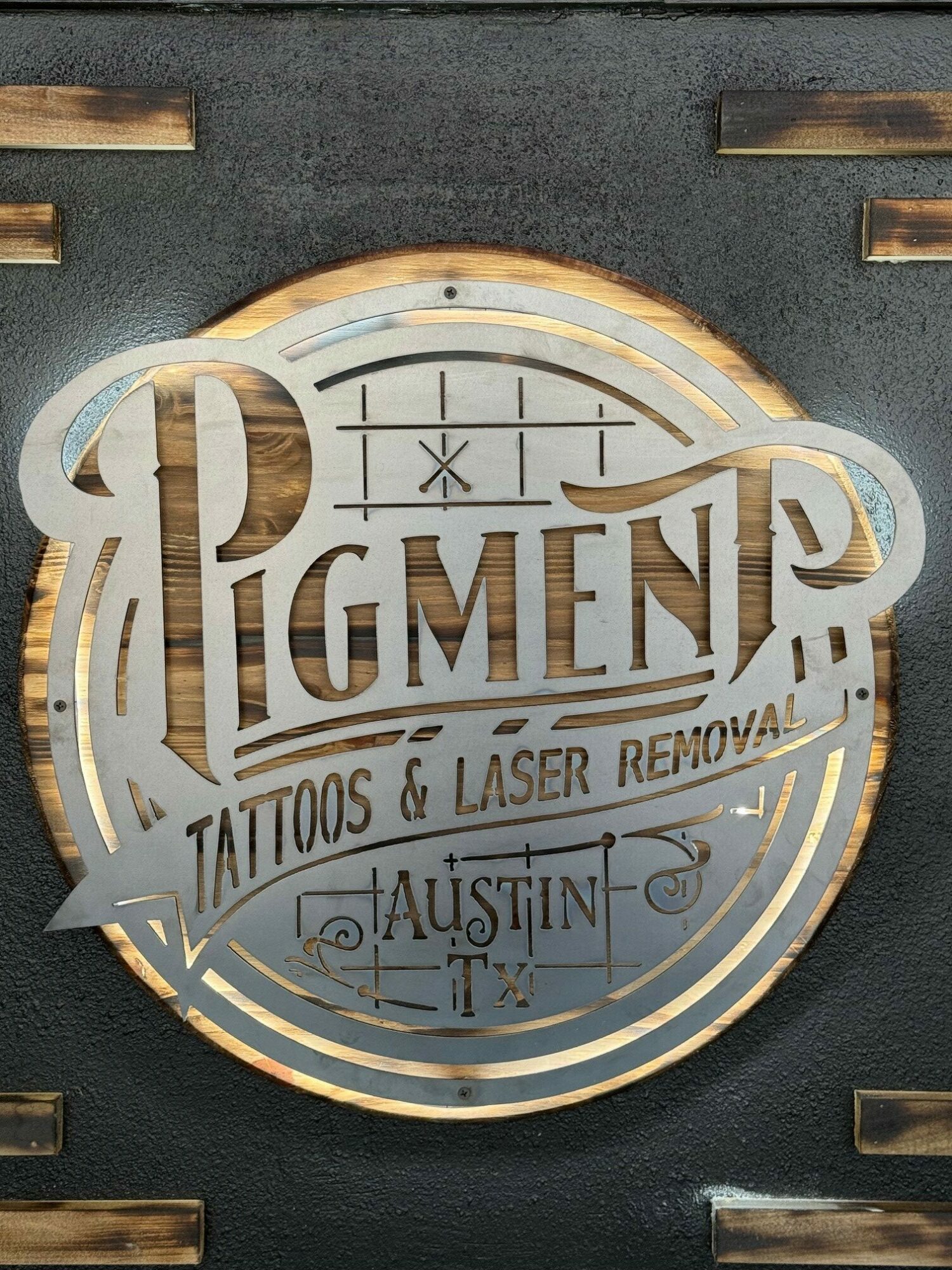 Circular sign with text and logo, mounted on a dark background, illuminated with a glow effect.