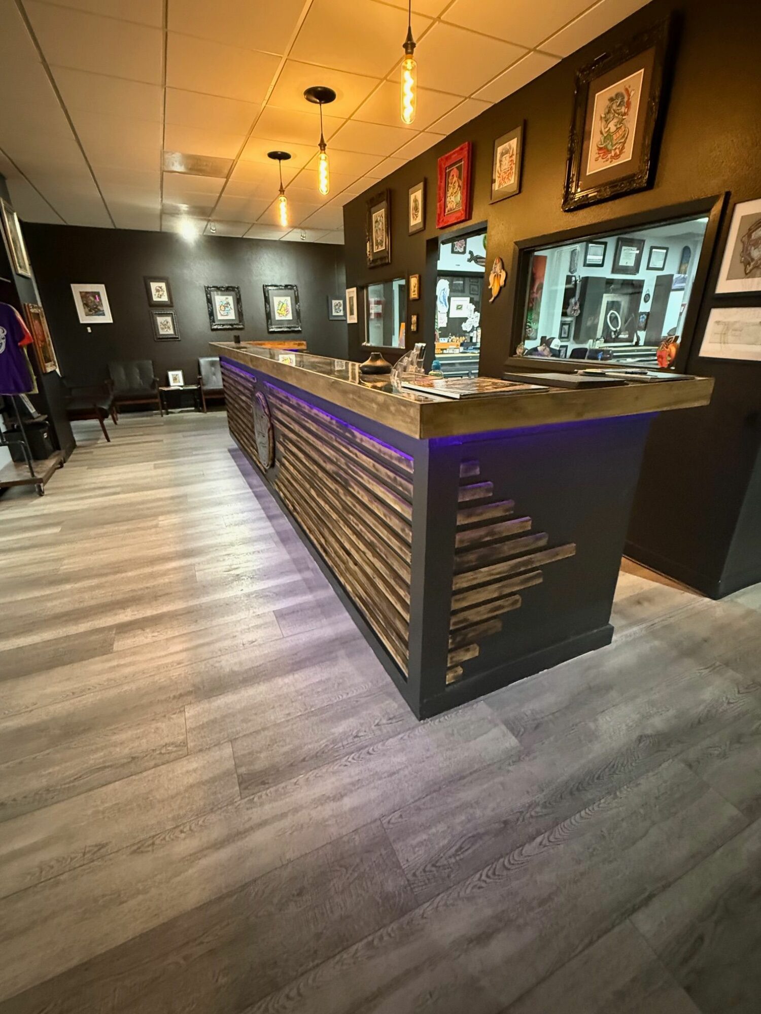 Exhibit with framed pictures and a display case in a gallery, viewed from the side, with wooden flooring.