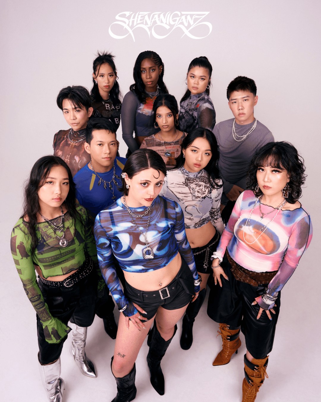 Group of ten young women standing together, wearing colorful and patterned clothing, posing against a plain background.