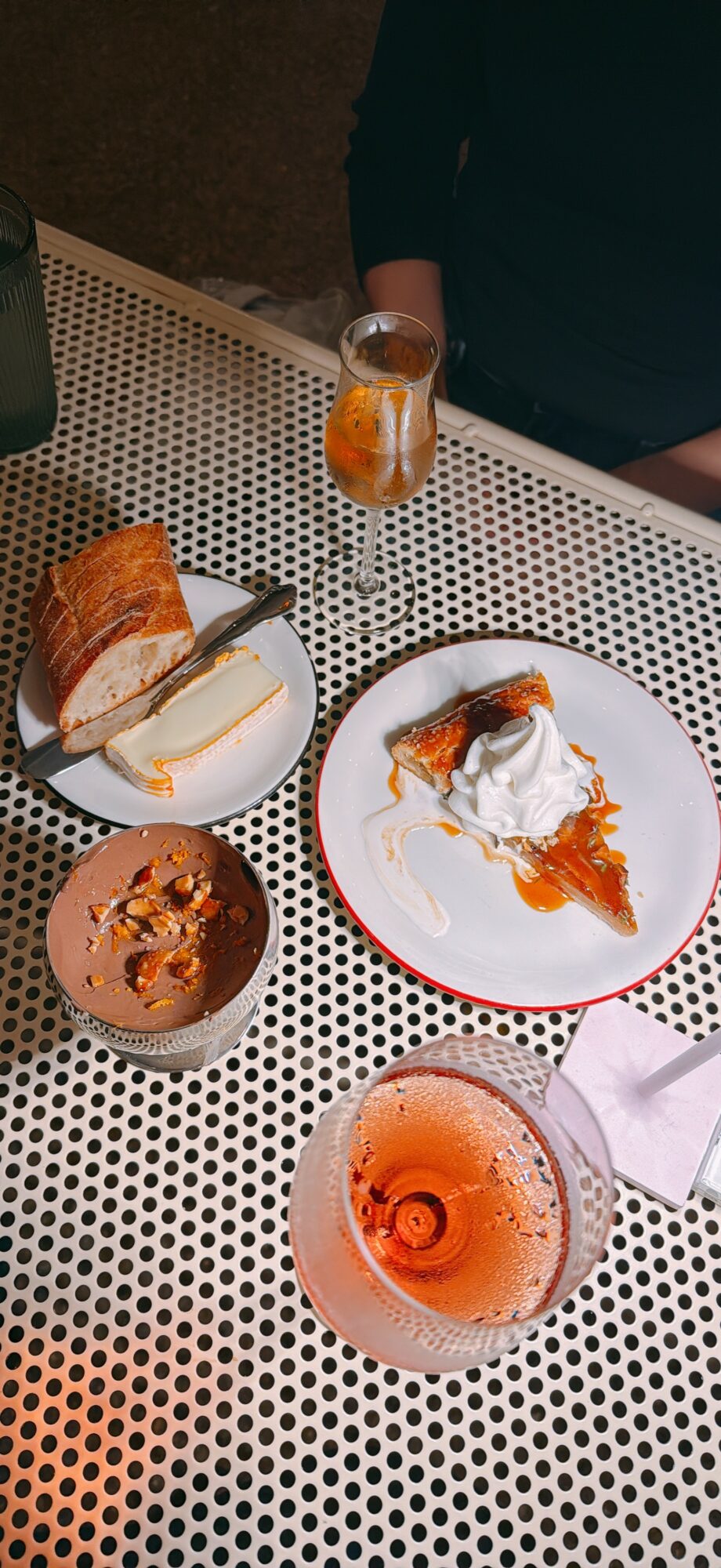 Various desserts and drinks on a perforated table, including cake slices, a bowl, and glasses with beverages.