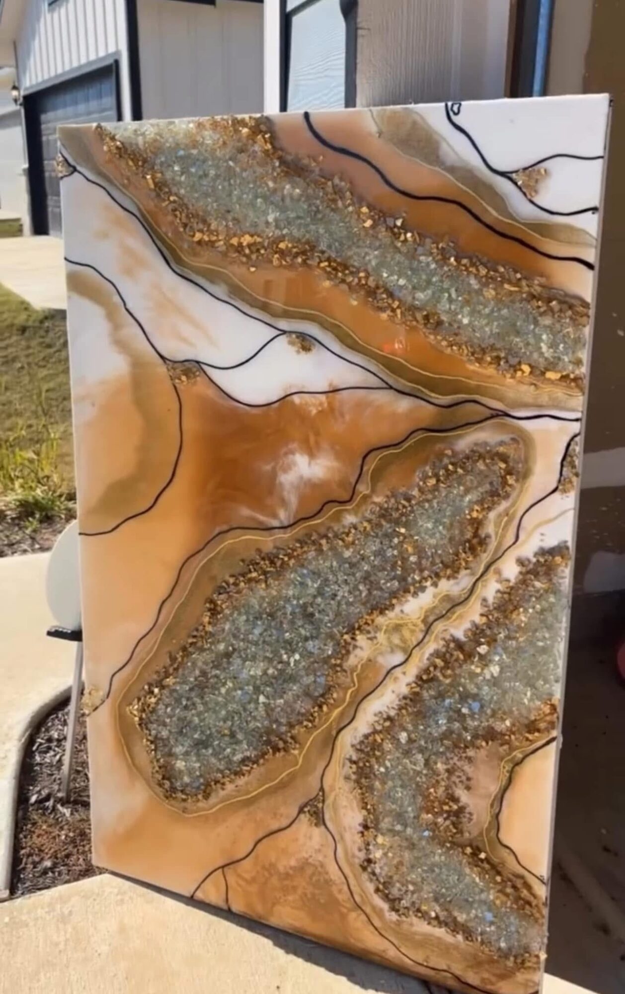 Decorative stone with gold, silver, and black accents, featuring layered, textured patterns and flowing lines.