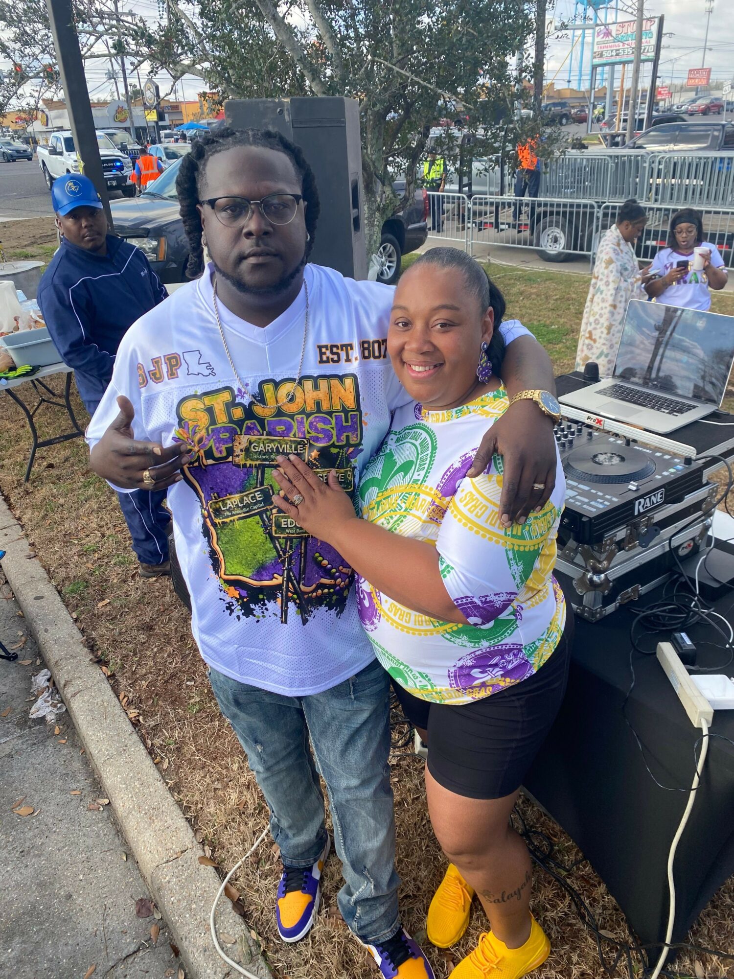 Two children standing outdoors, one wearing a colorful shirt and the other in a white T-shirt with a graphic, both smiling.