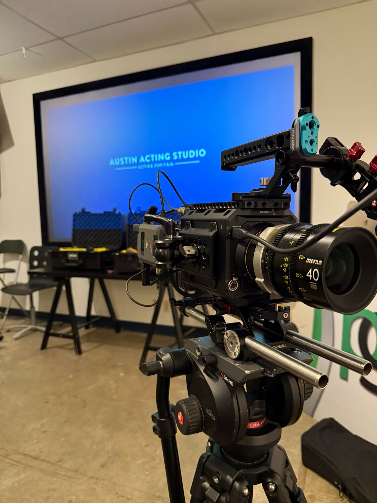 Camera setup with a monitor displaying blue background and text, on a tripod with various equipment, viewed from above.