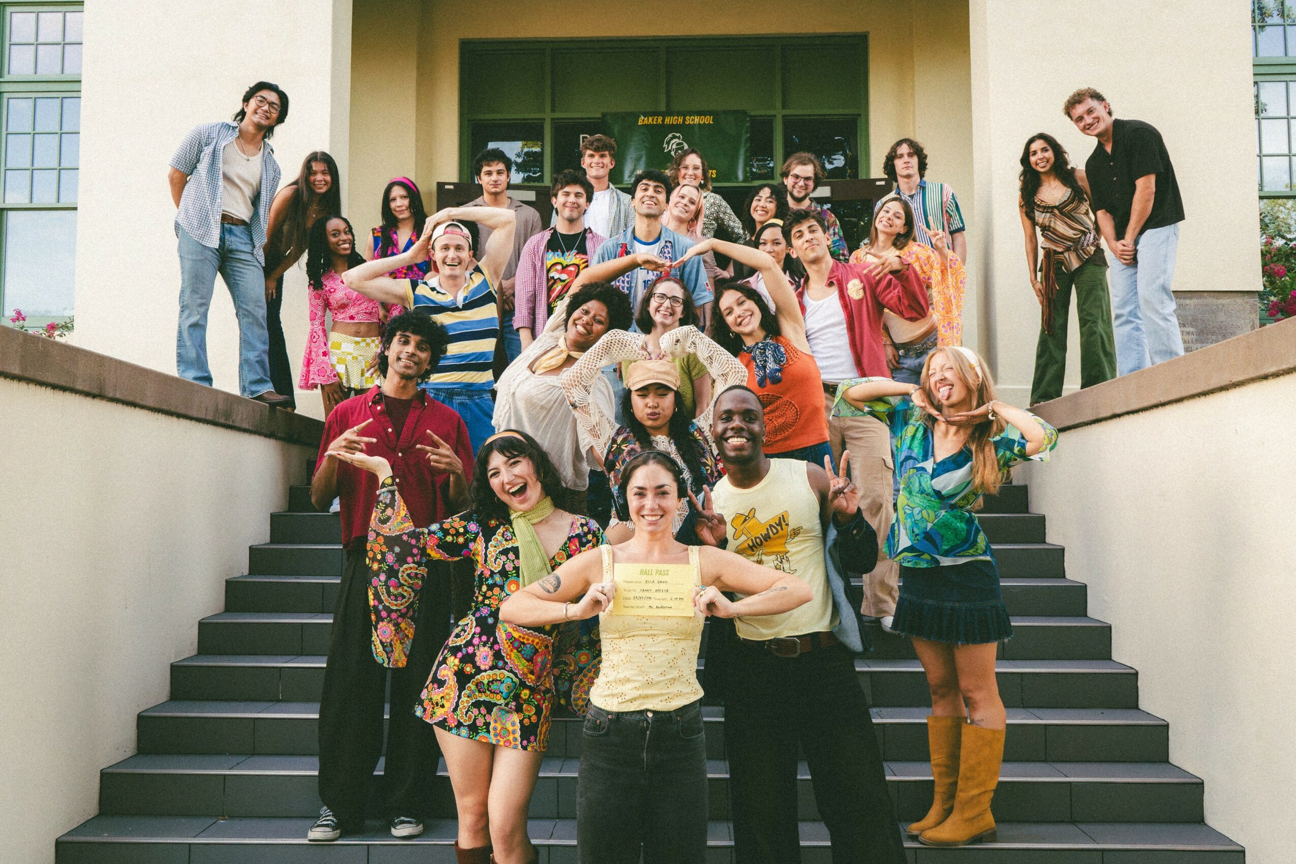 Group of diverse people standing on stairs outside a building, smiling and posing for a photo.