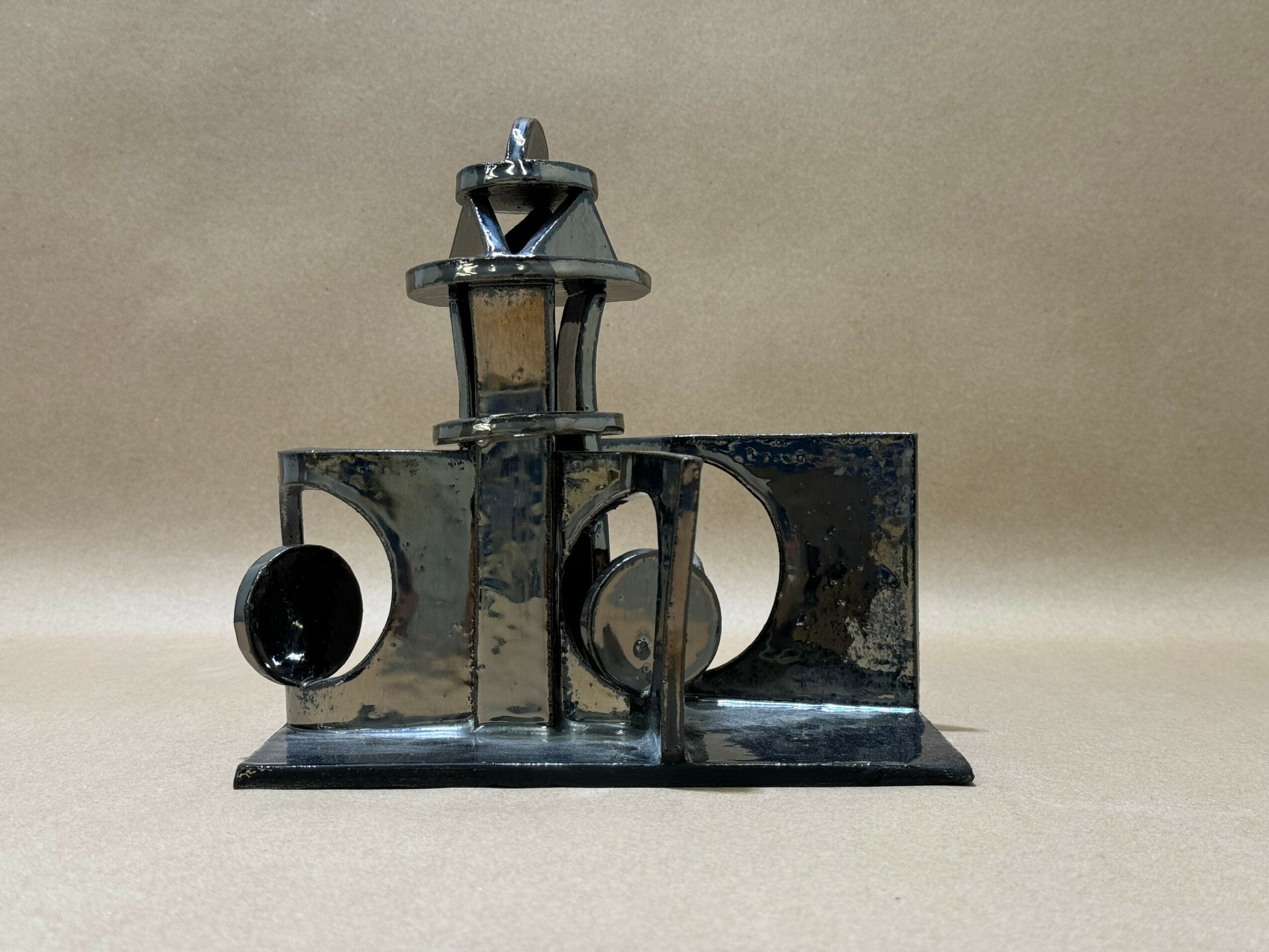 Small black metal lantern with two circular openings, placed on a flat surface against a plain background.