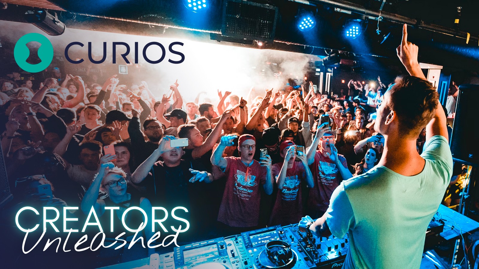 DJ performing at a crowded event with people dancing and raising hands, stage lights shining, and a banner reading 'CREATORS Unleashed'.