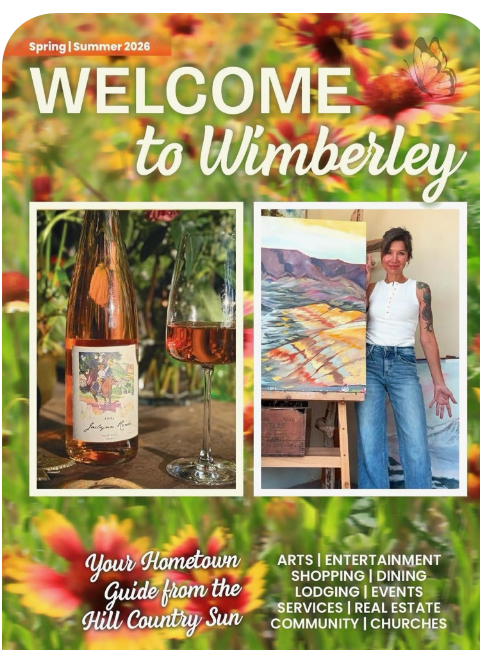 Welcome sign with flowers, wine bottle, glass, and a woman standing next to an outdoor painting, celebrating Wimberley.
