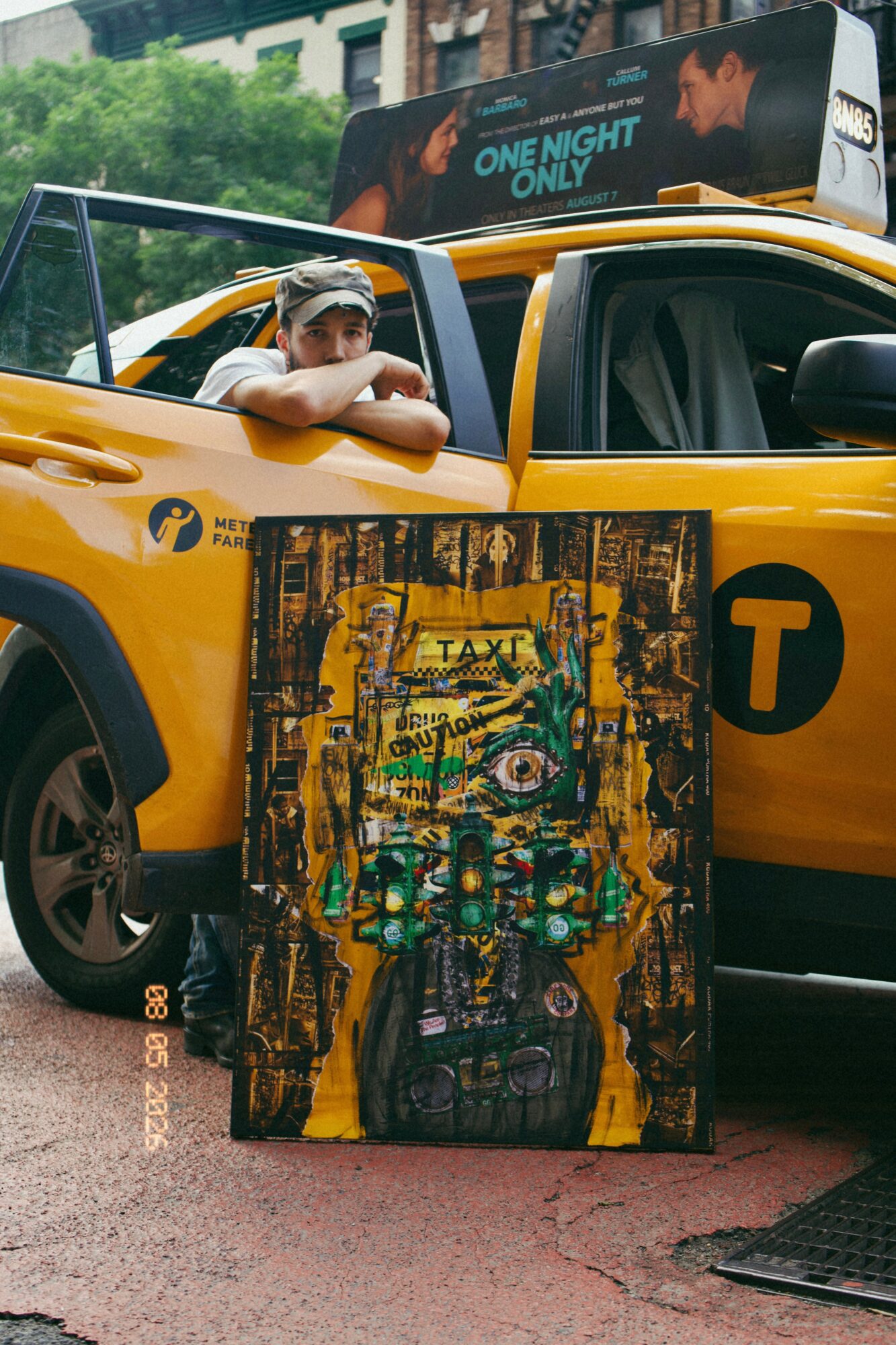 Child leaning on a yellow taxi cab with a colorful painting in front, city street background, person in background on bus.